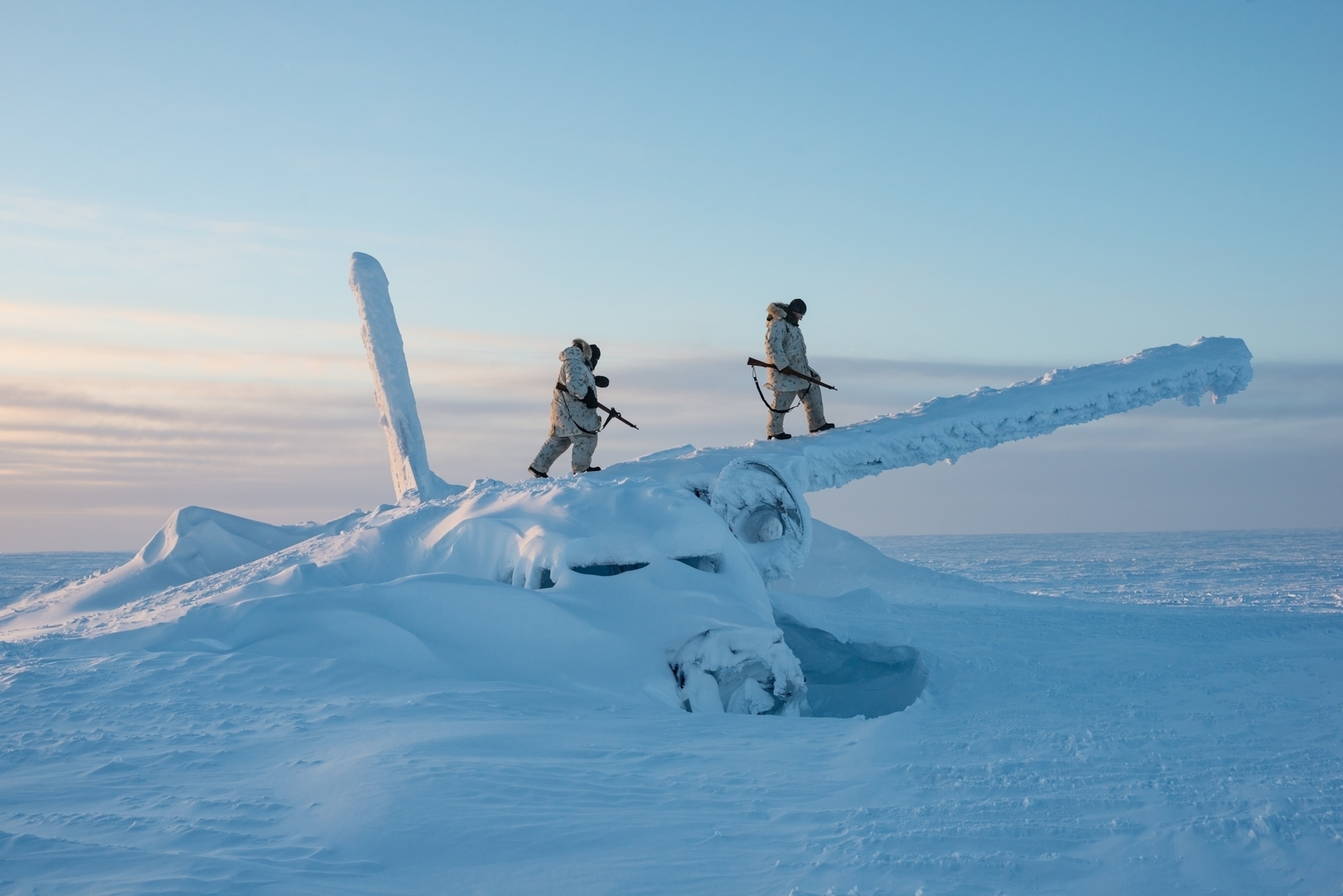 two persons with firearms on frozen in ice and snow airplane.