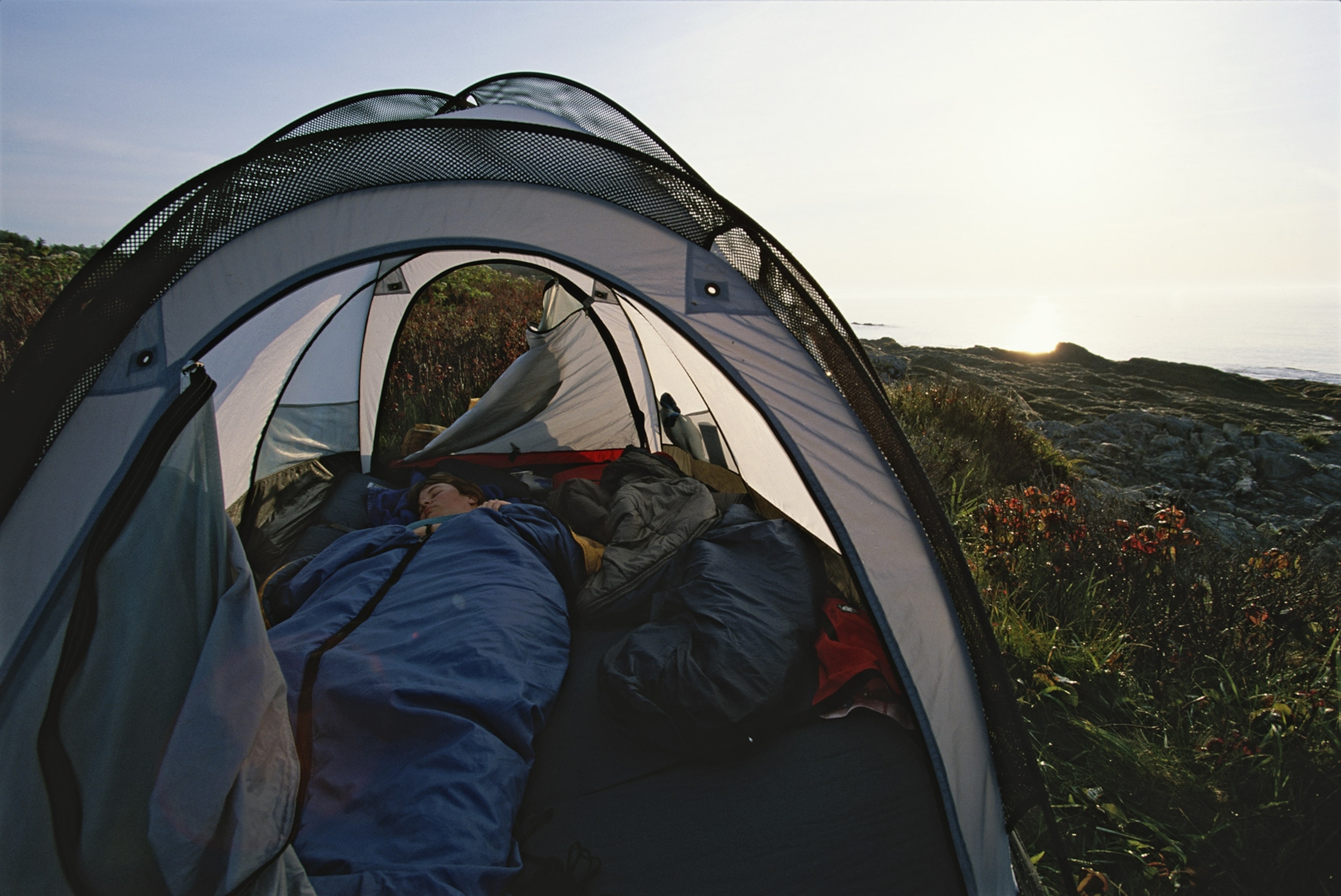 A woman sleeps in her tent as the sun rises on Jewel Island