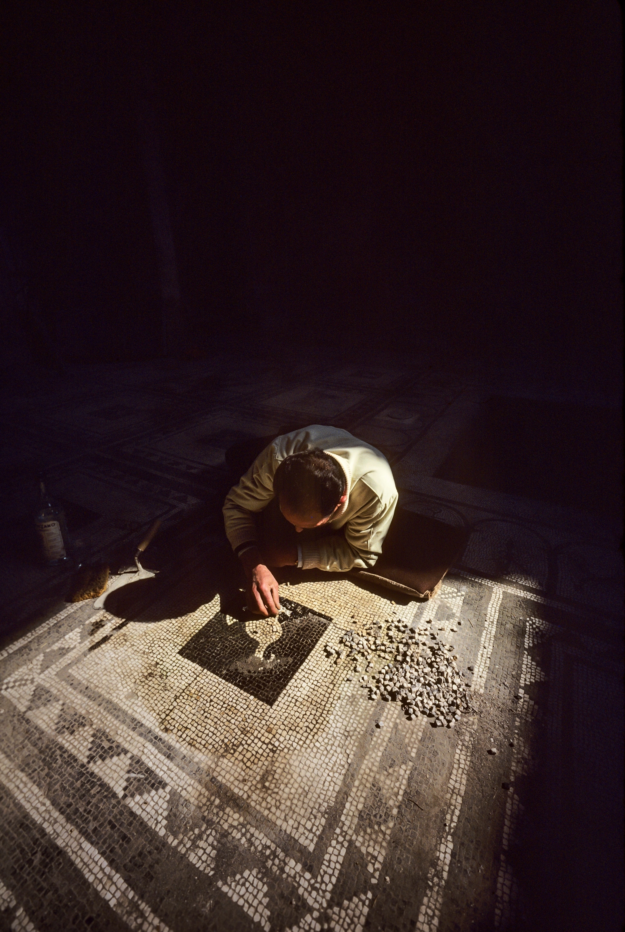 An photograph of a technician restoring the mosaic in the entrance hall at the In the House of Paquius Proculus in Pompeii, Campania, Italy.