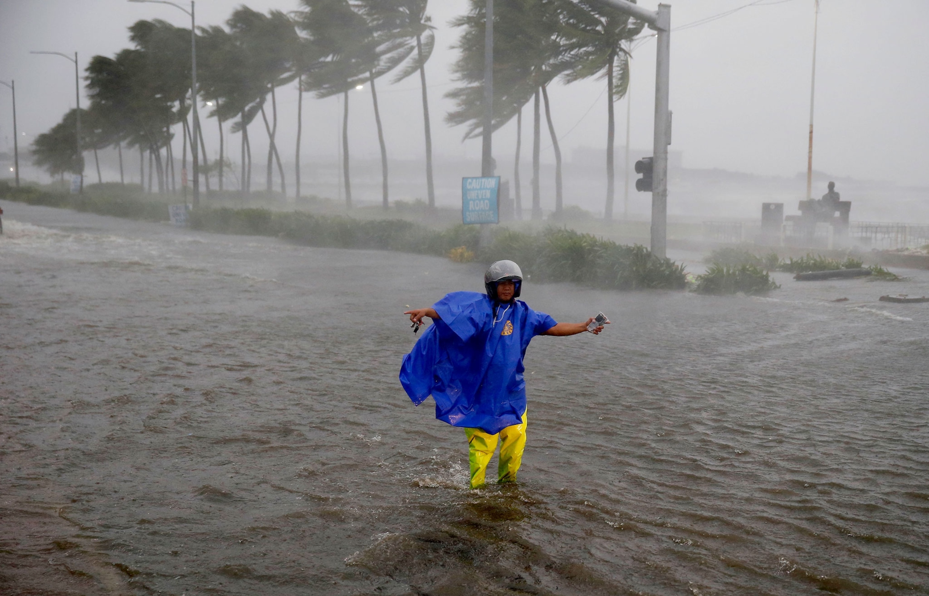 a man directing traffic to avoid a flooded street.