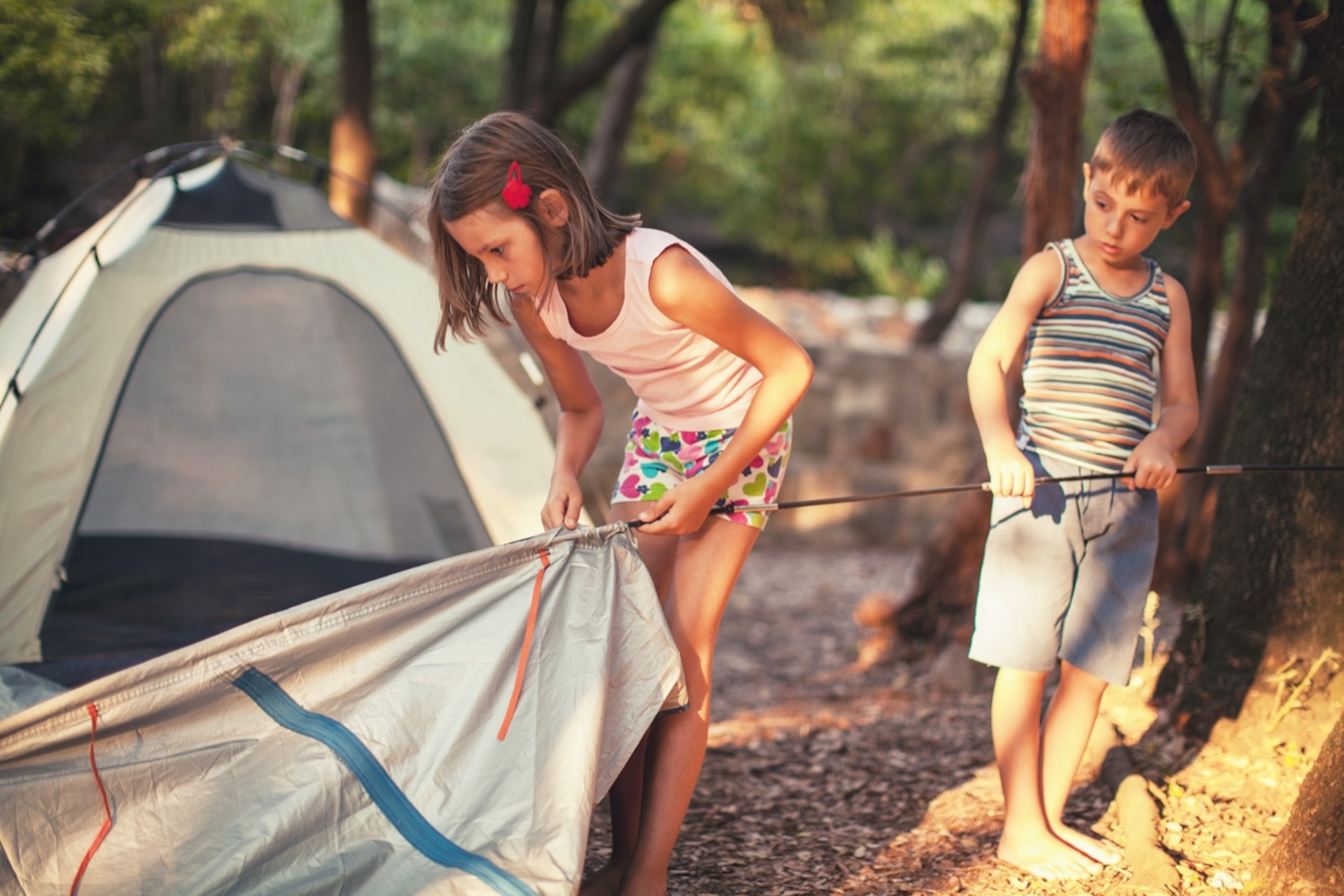 Little boy and girl preparing and setting up tent for camping. Montenegro.