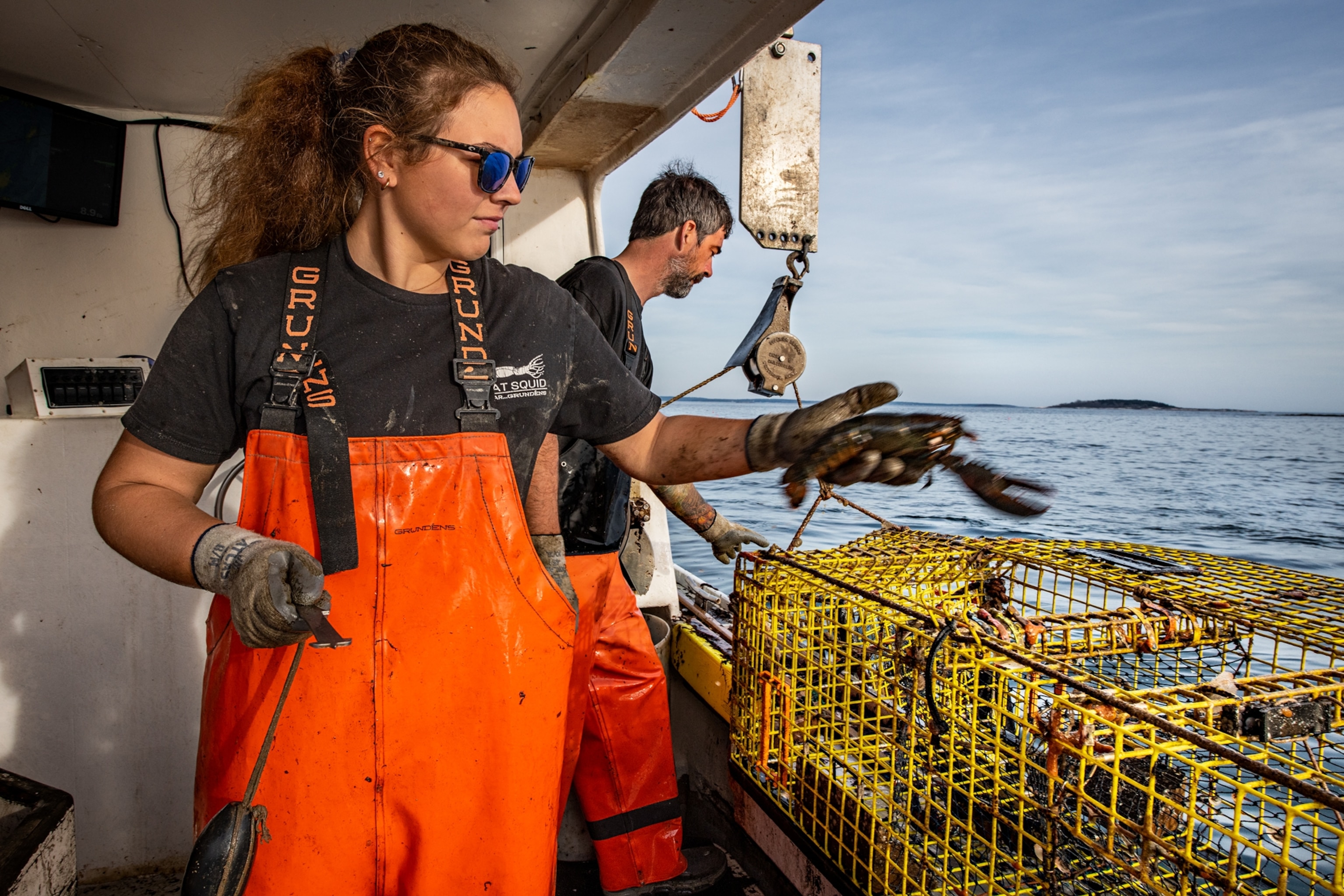 Jocelyn Coombs holds a lobster on a boat by the coast of Orrs Island, Maine.