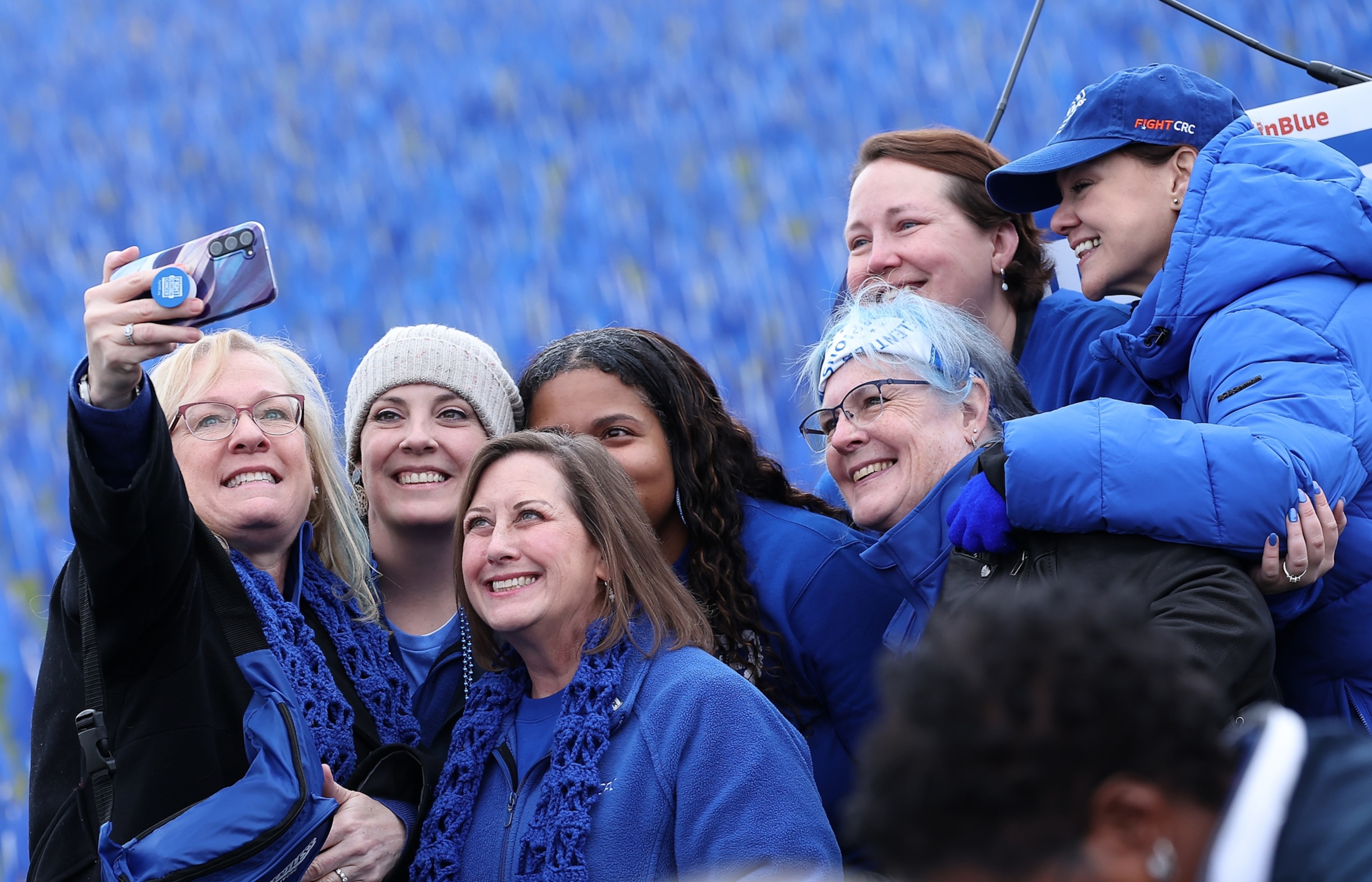 A group of cancer survivors, dressed in blue, pose for a selfie in front of a colorectal cancer awareness installation.