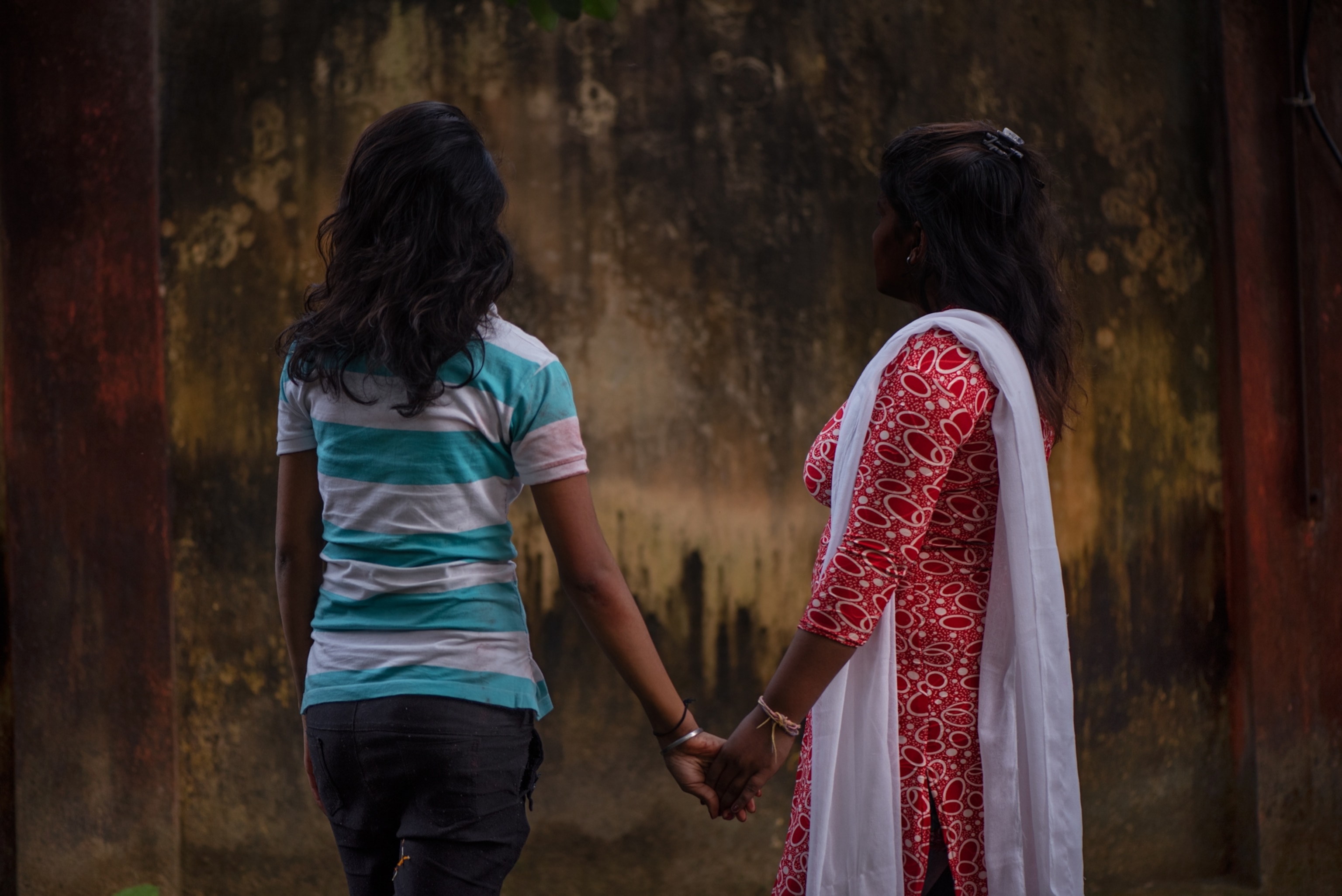 two girls facing away from the camera holding hands