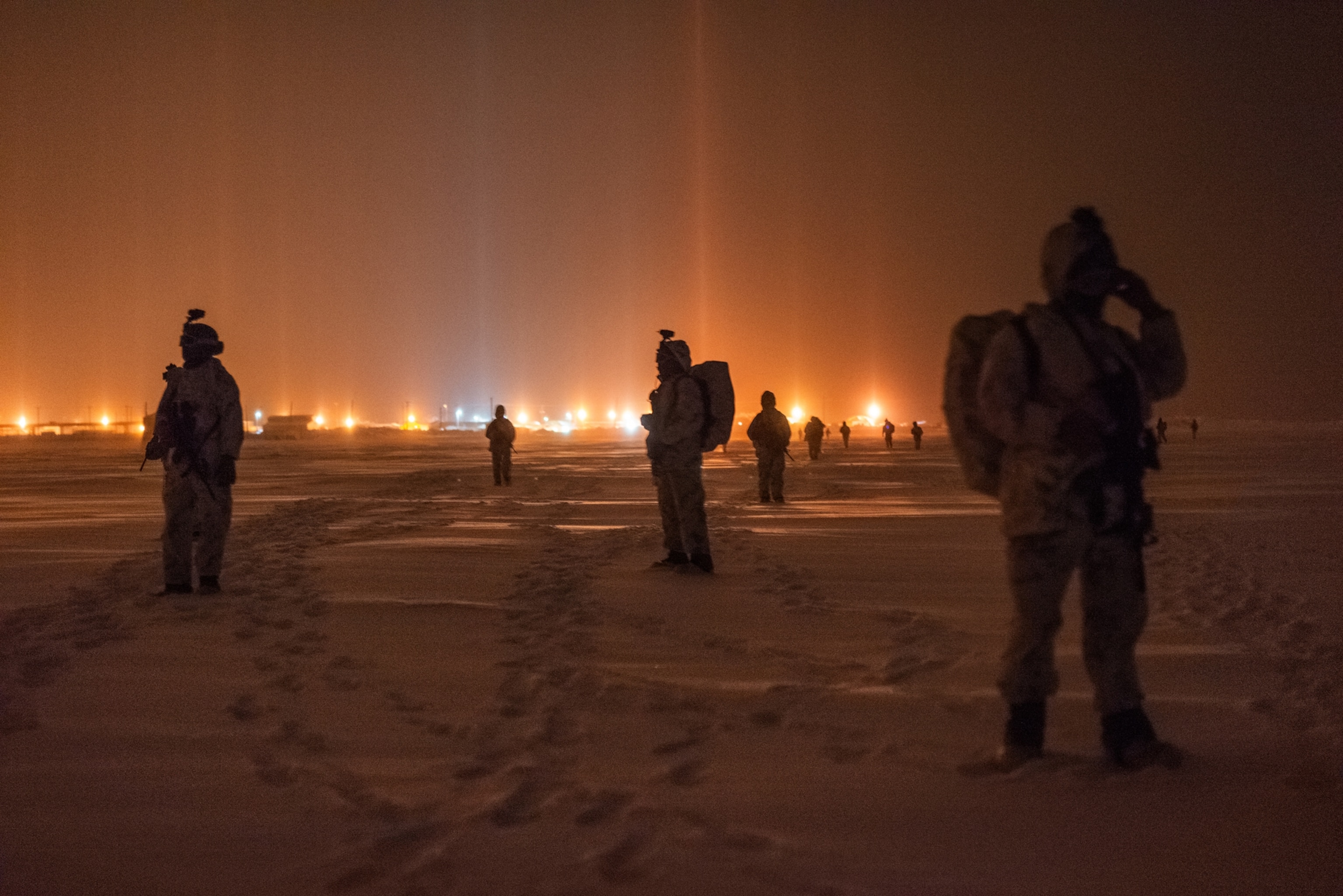 soldiers in darkness on ice looking at glowing horizon.