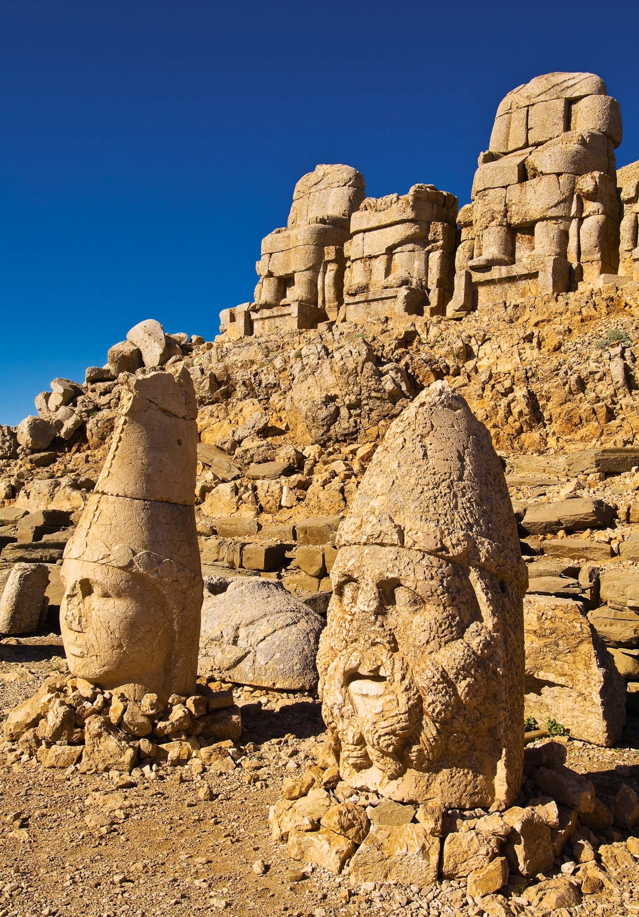 Another view of the head statues in front of the their bodies at the tomb mound with a blue sky