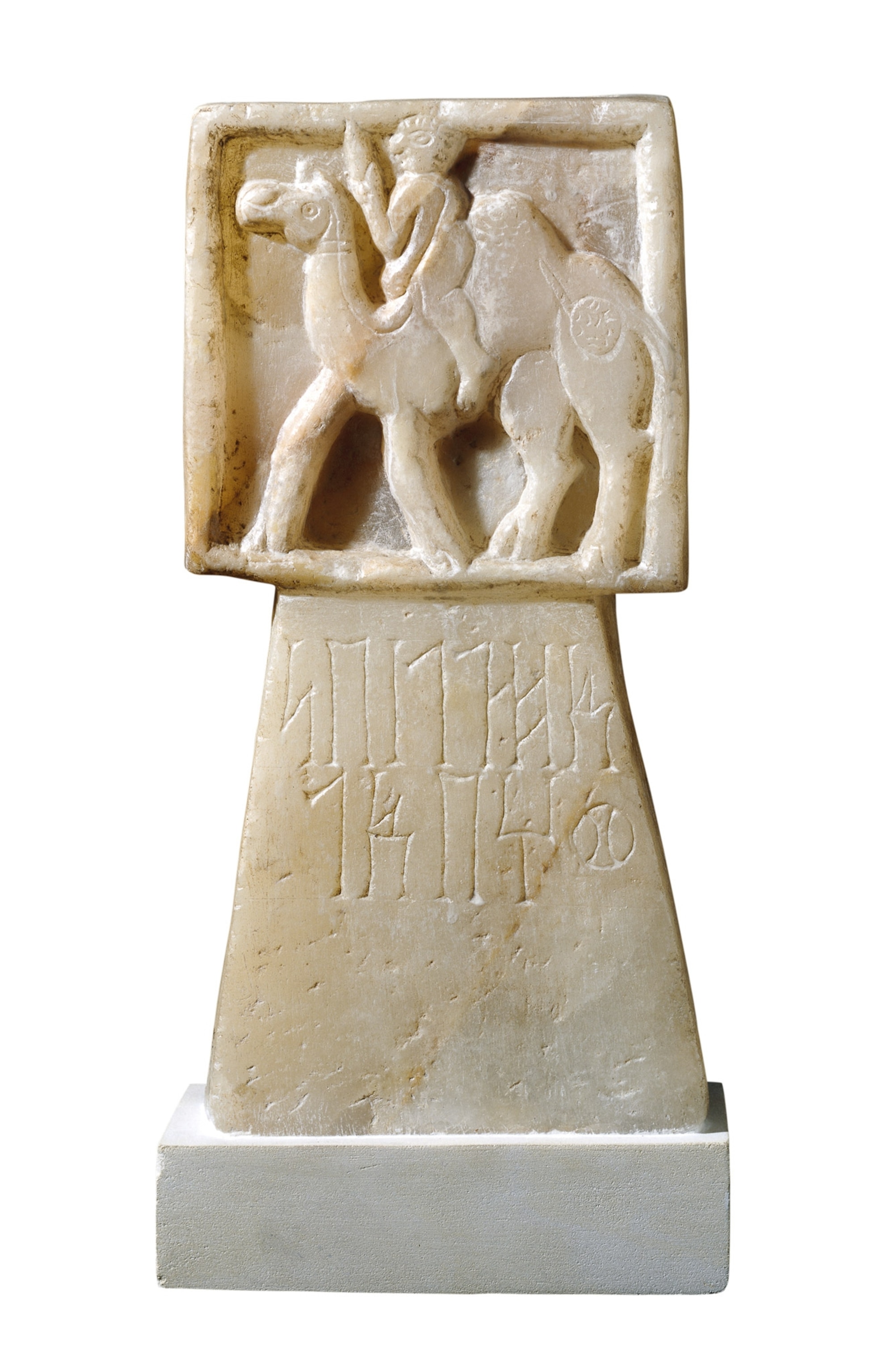 A white stone carving of a person on a camel