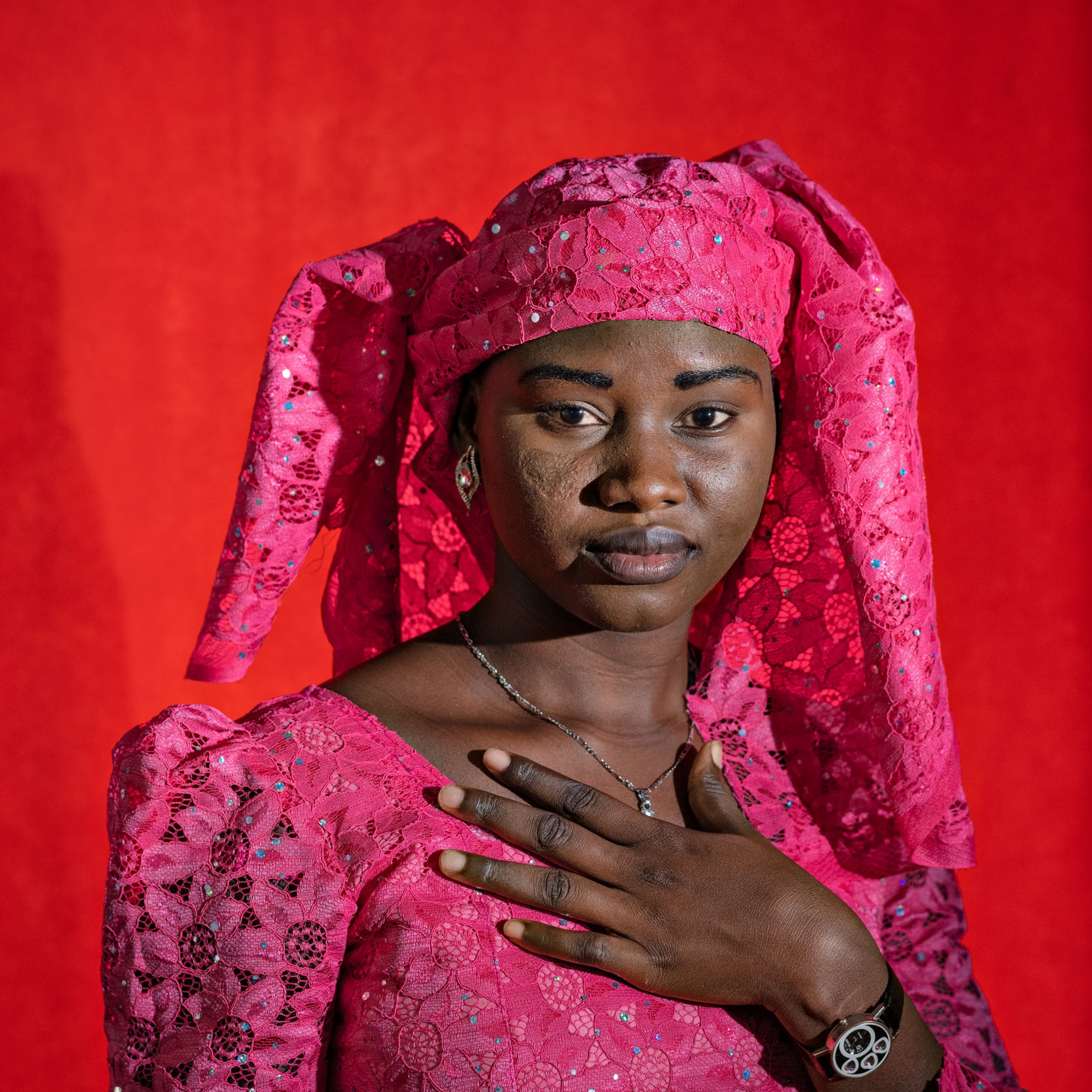 young woman in pink against a bright red background standing for a portrait