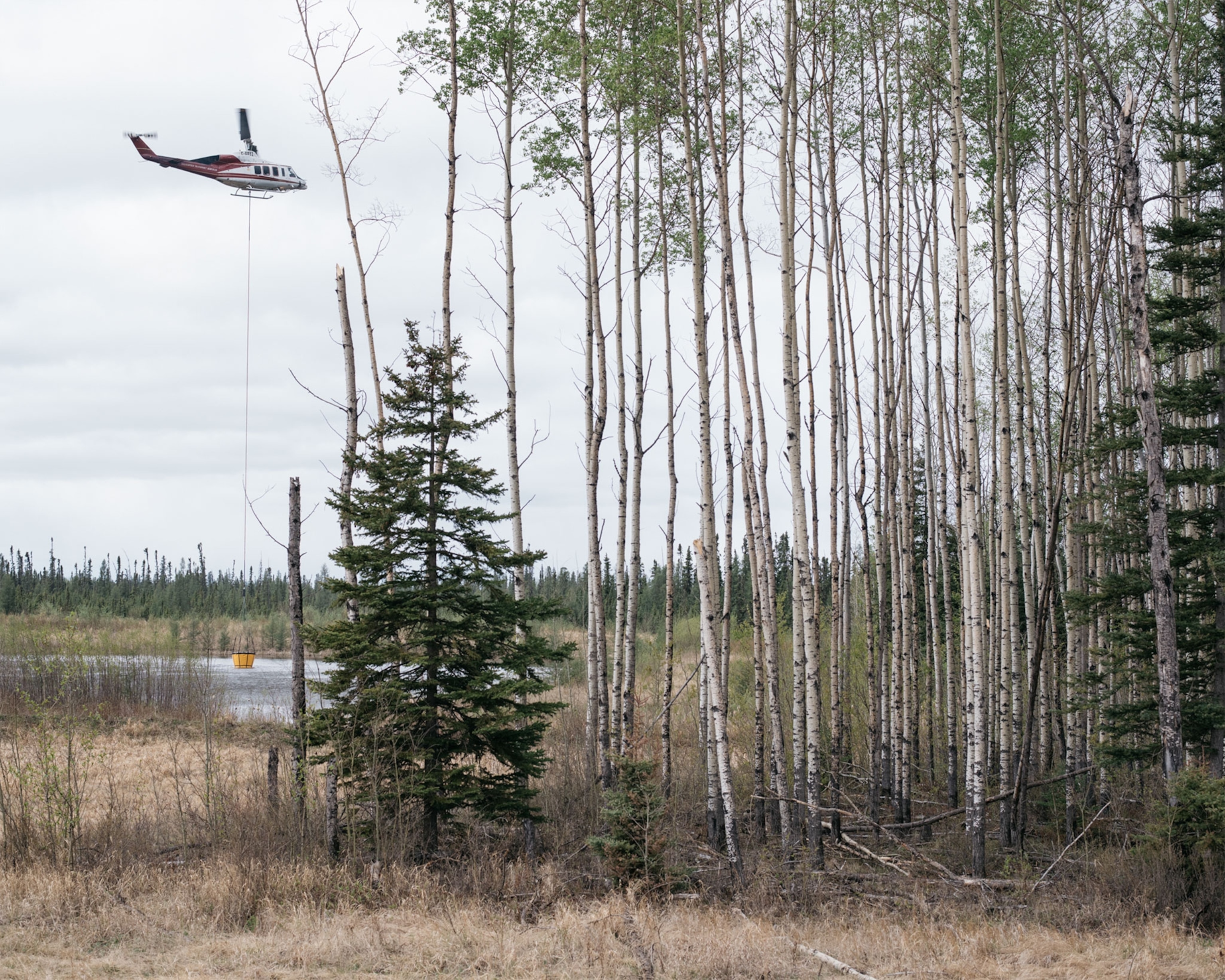 a helicopter picking up water to help fight a wildfire in Canada