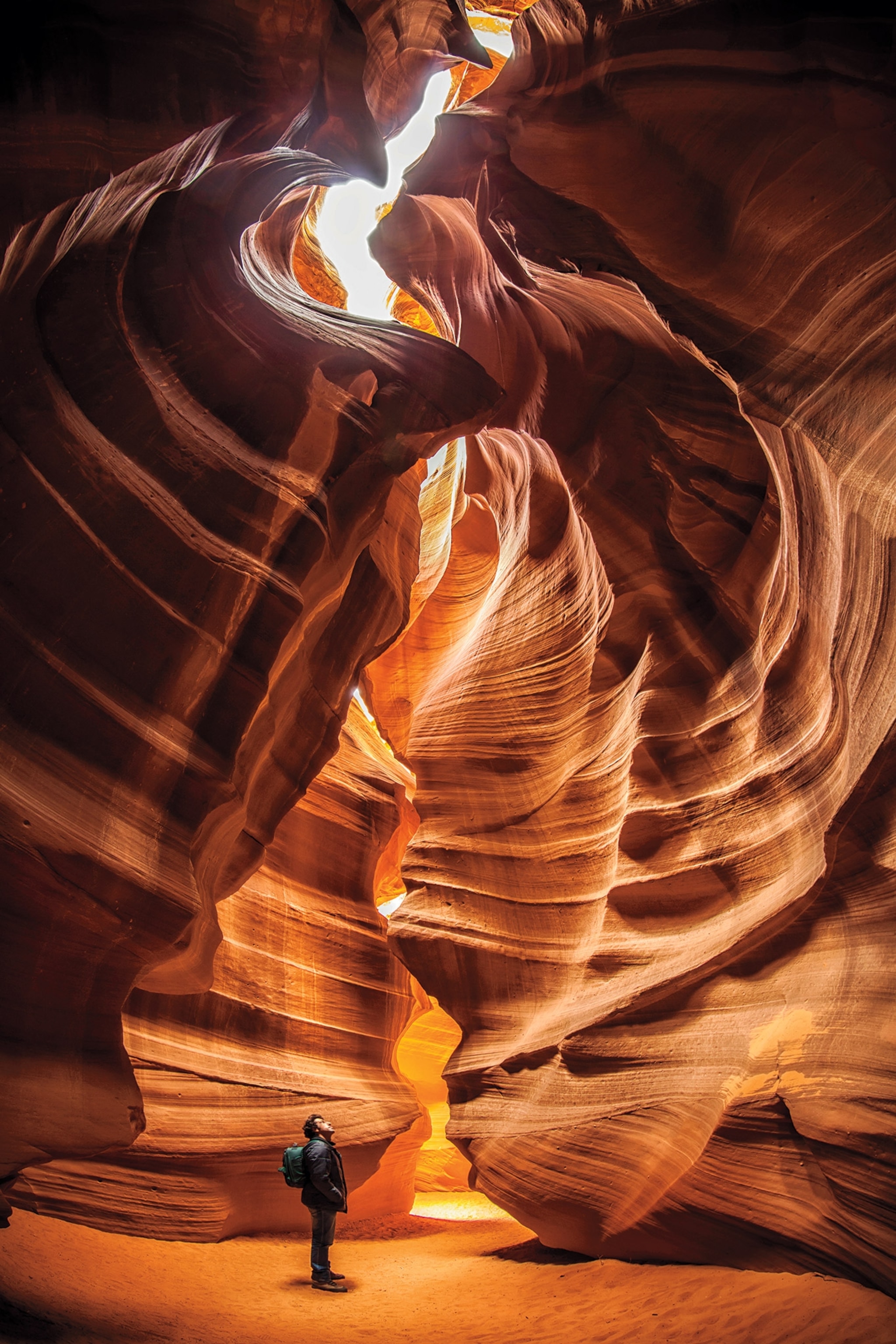Light pours into a cavern as a man looks up.