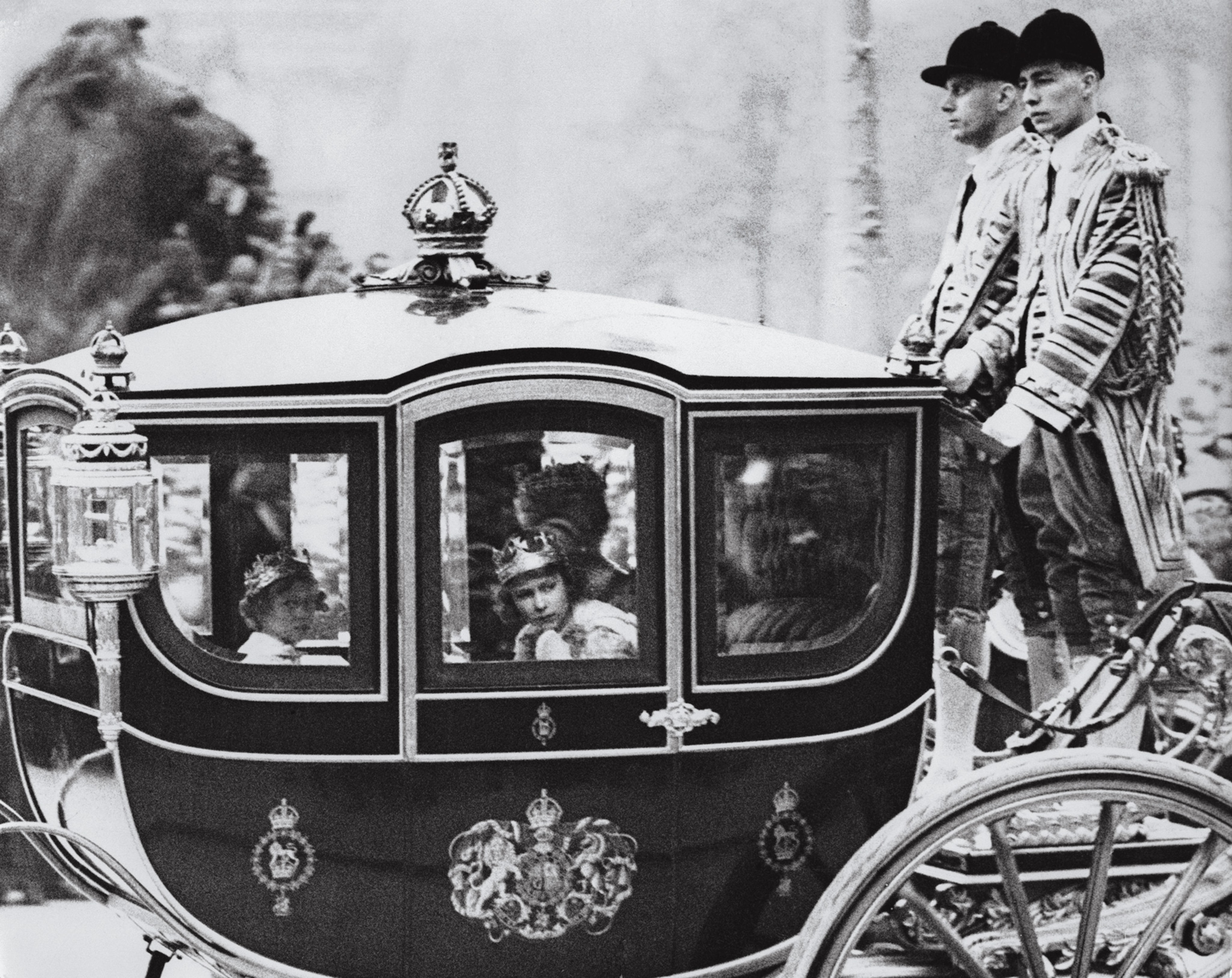 Princesses Margaret and Elizabeth (right) peek out of a carriage window after their parents’ coronation in 1937.