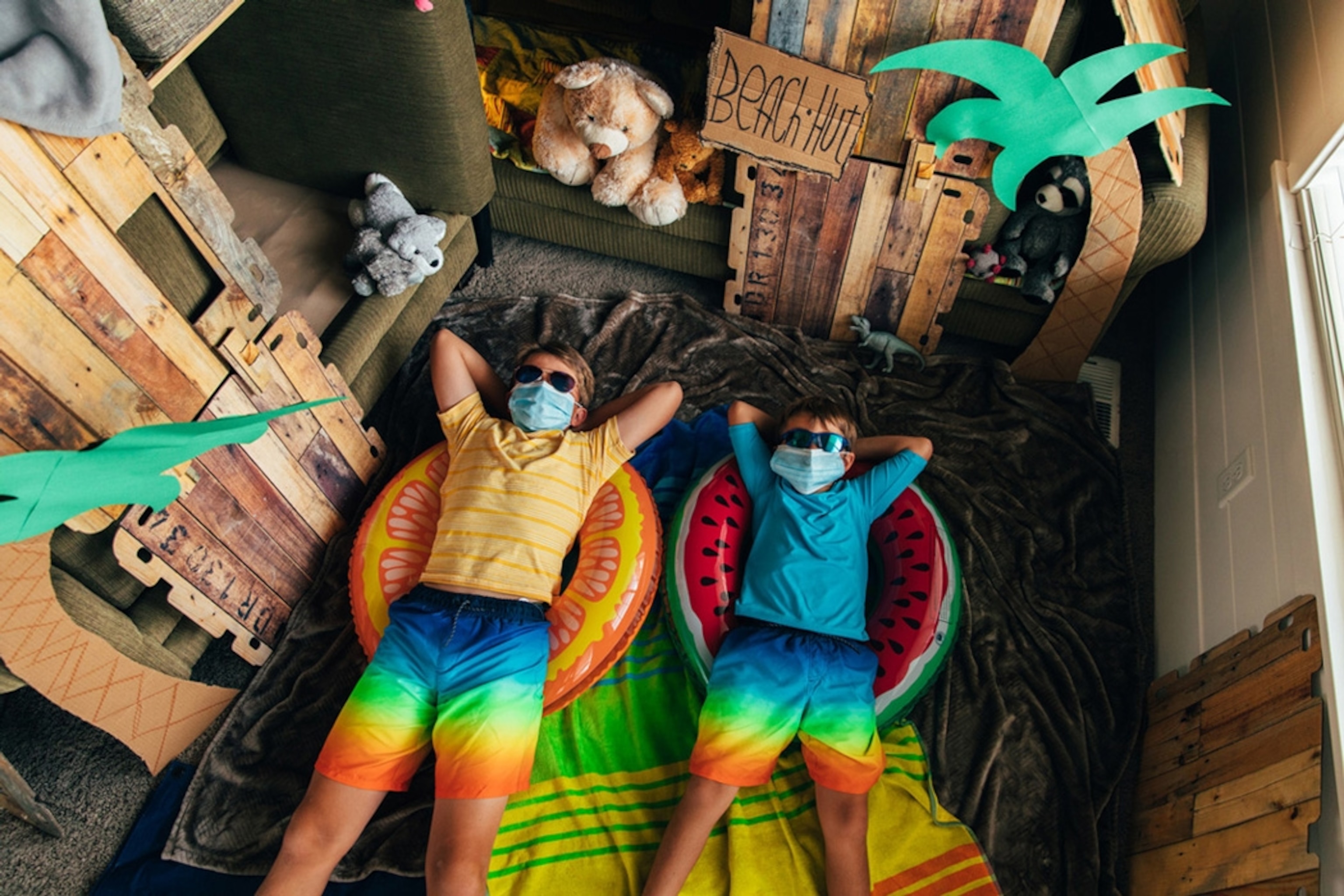 Young brothers are ready to go to the beach they have made in their home. The coronavirus quarantine has forced them from vacation mode to staycation mode. They are using the imagination by building couch fort into a beach hut.
