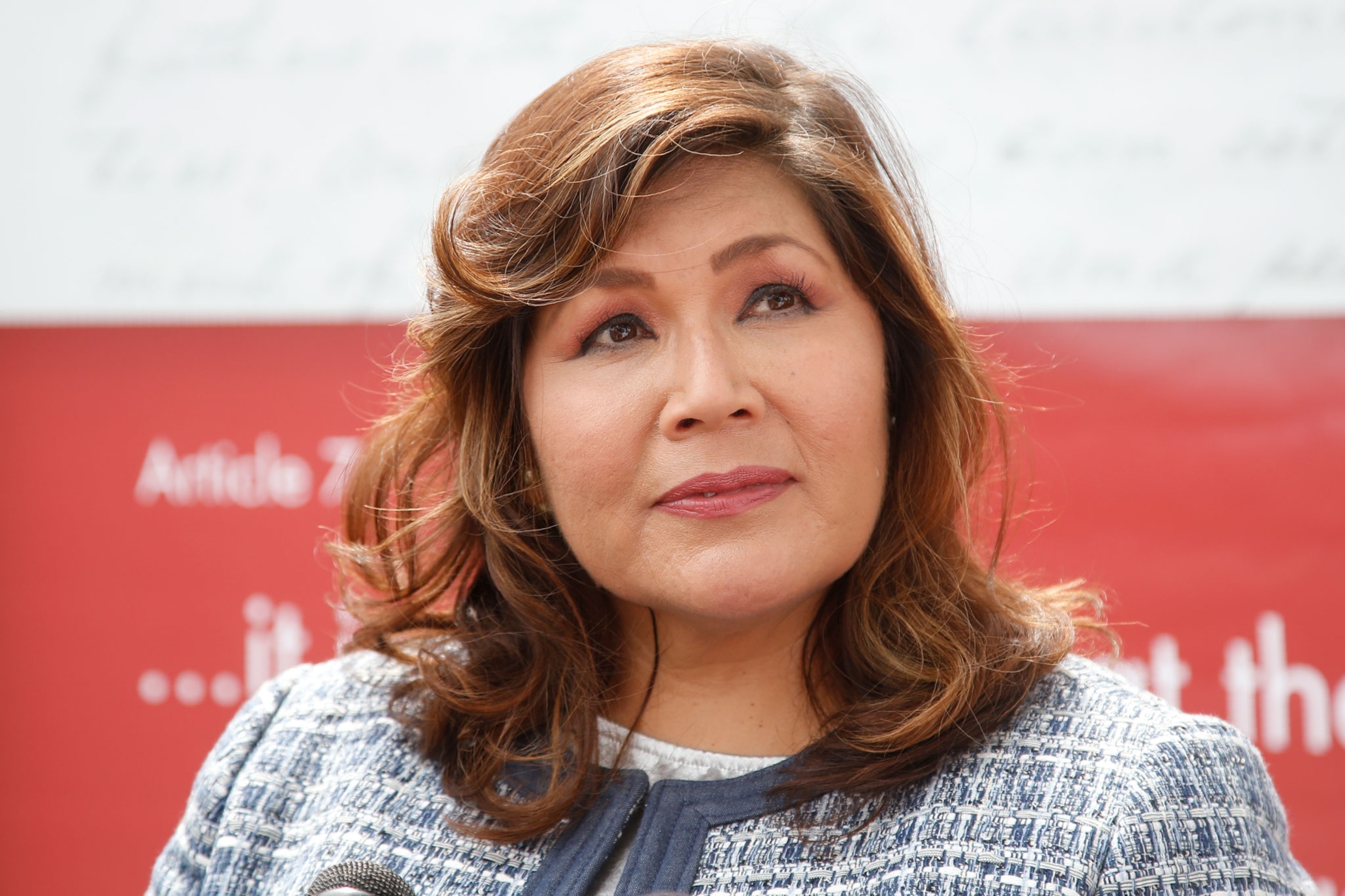 a woman listens to a question at a news conference
