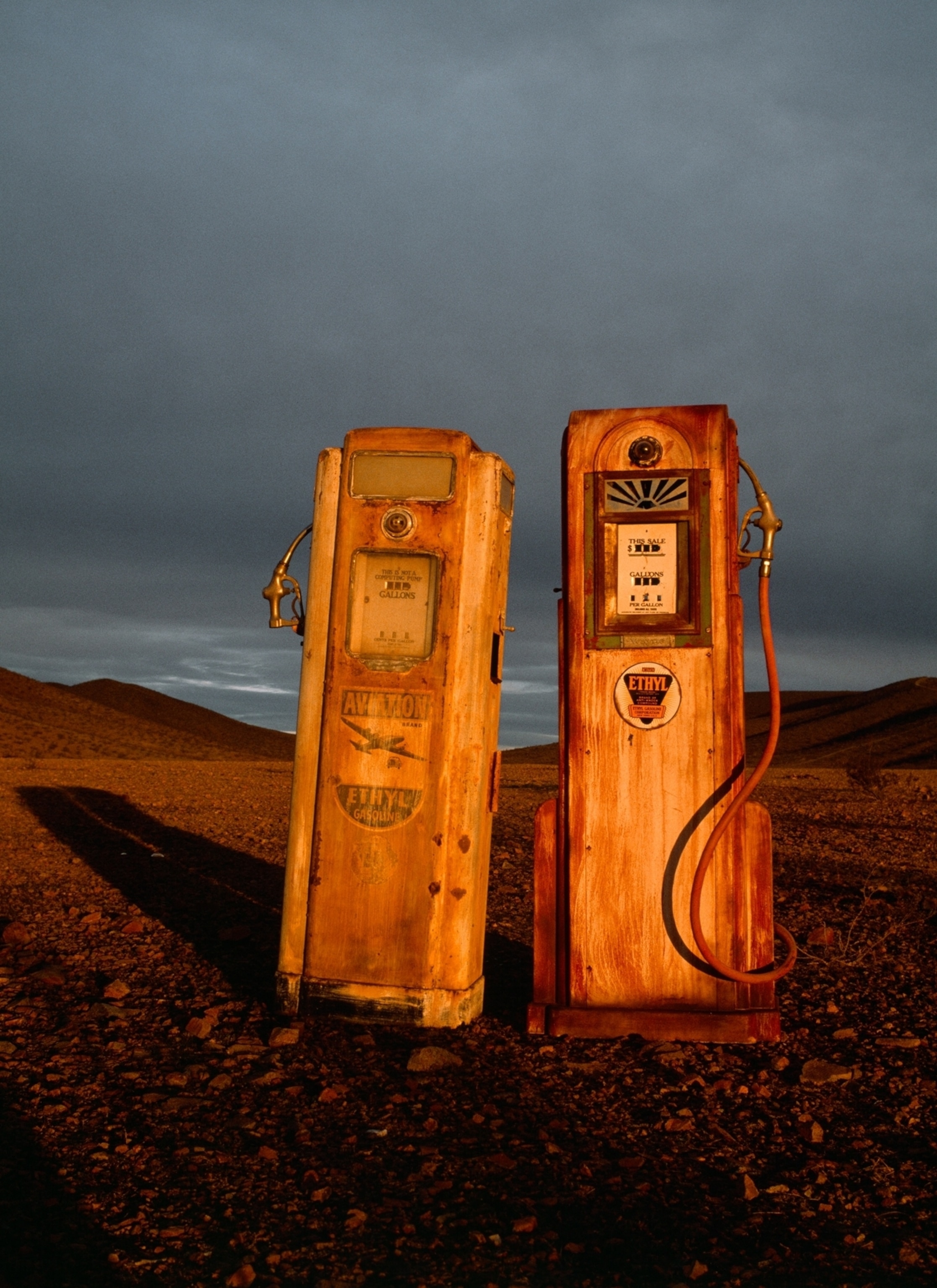 two pair of vintage gas pumps in a desert landscape.