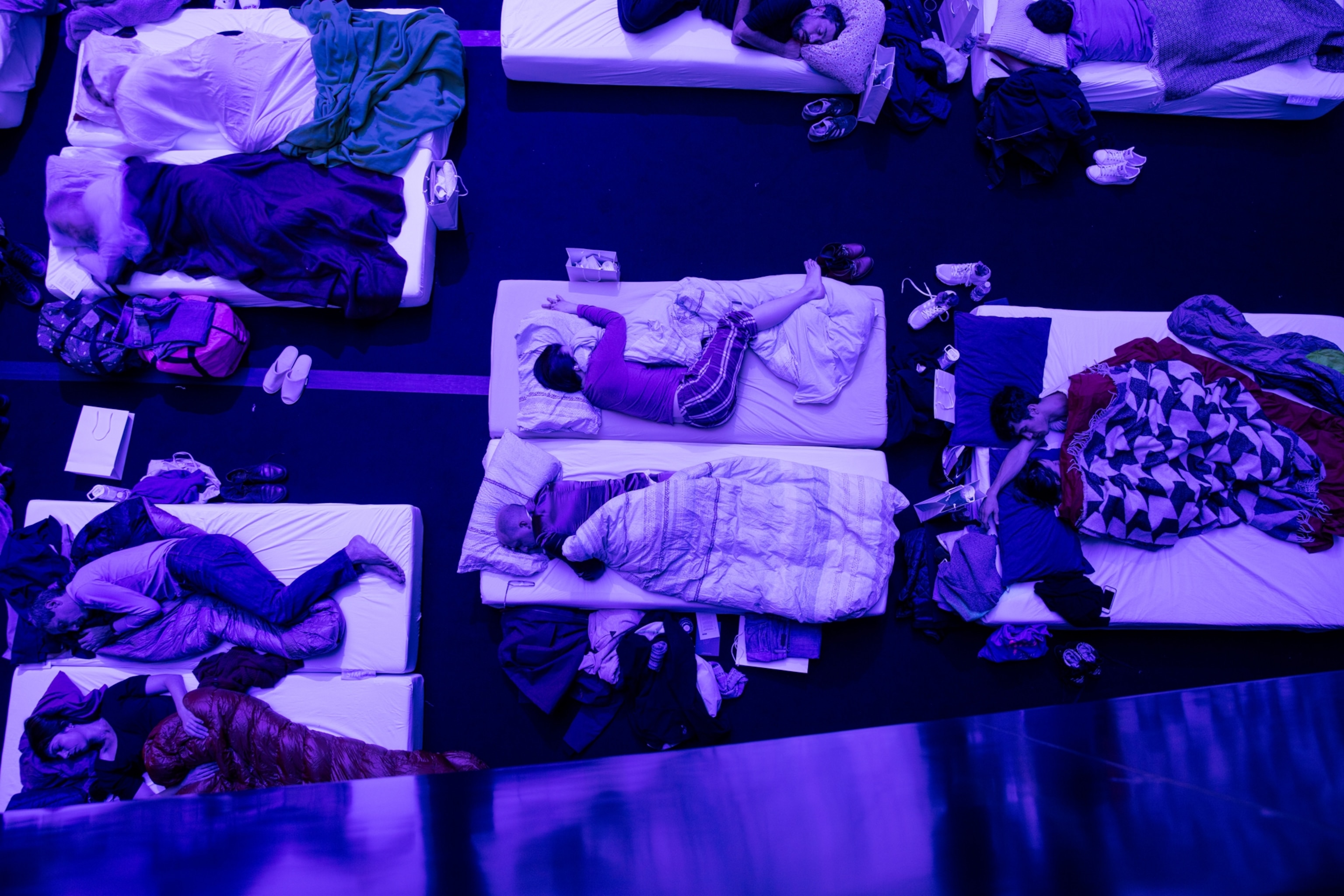 an aerial view of people sleeping on mattress at a concert revolving around sleep