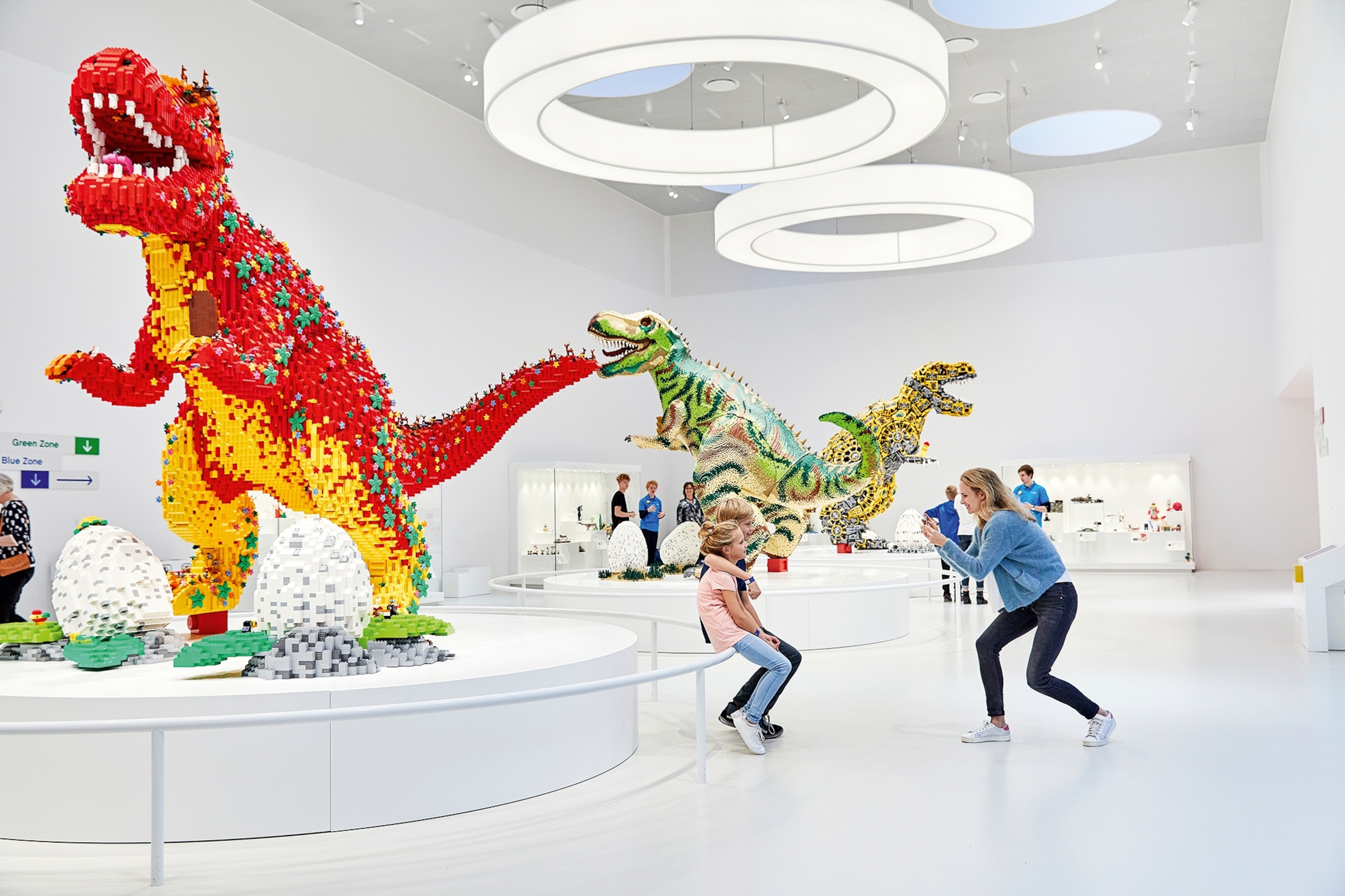 Parent takes a photo of children in front of a lego statue in a museum