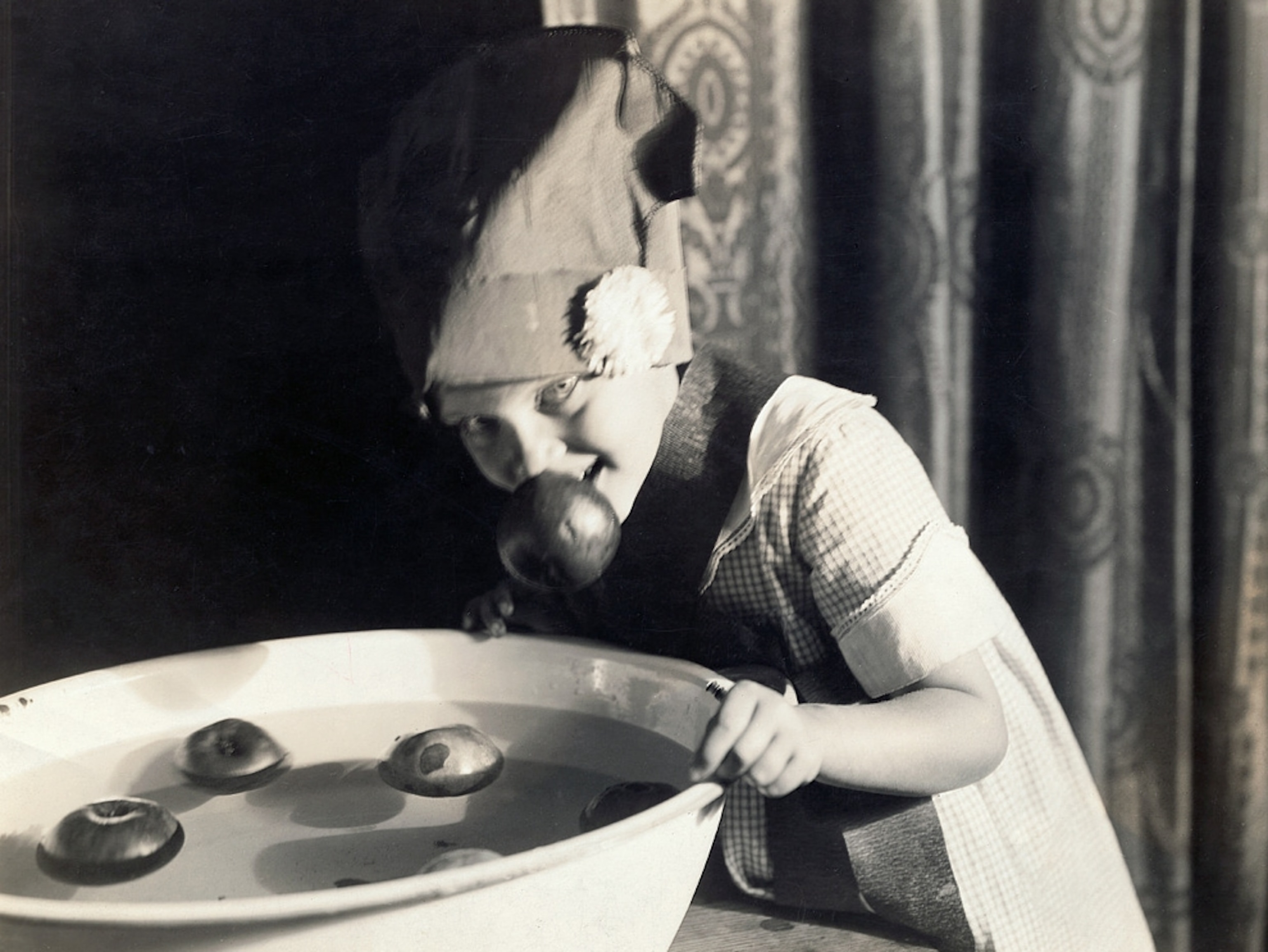 a girl bobbing for apples on Halloween.