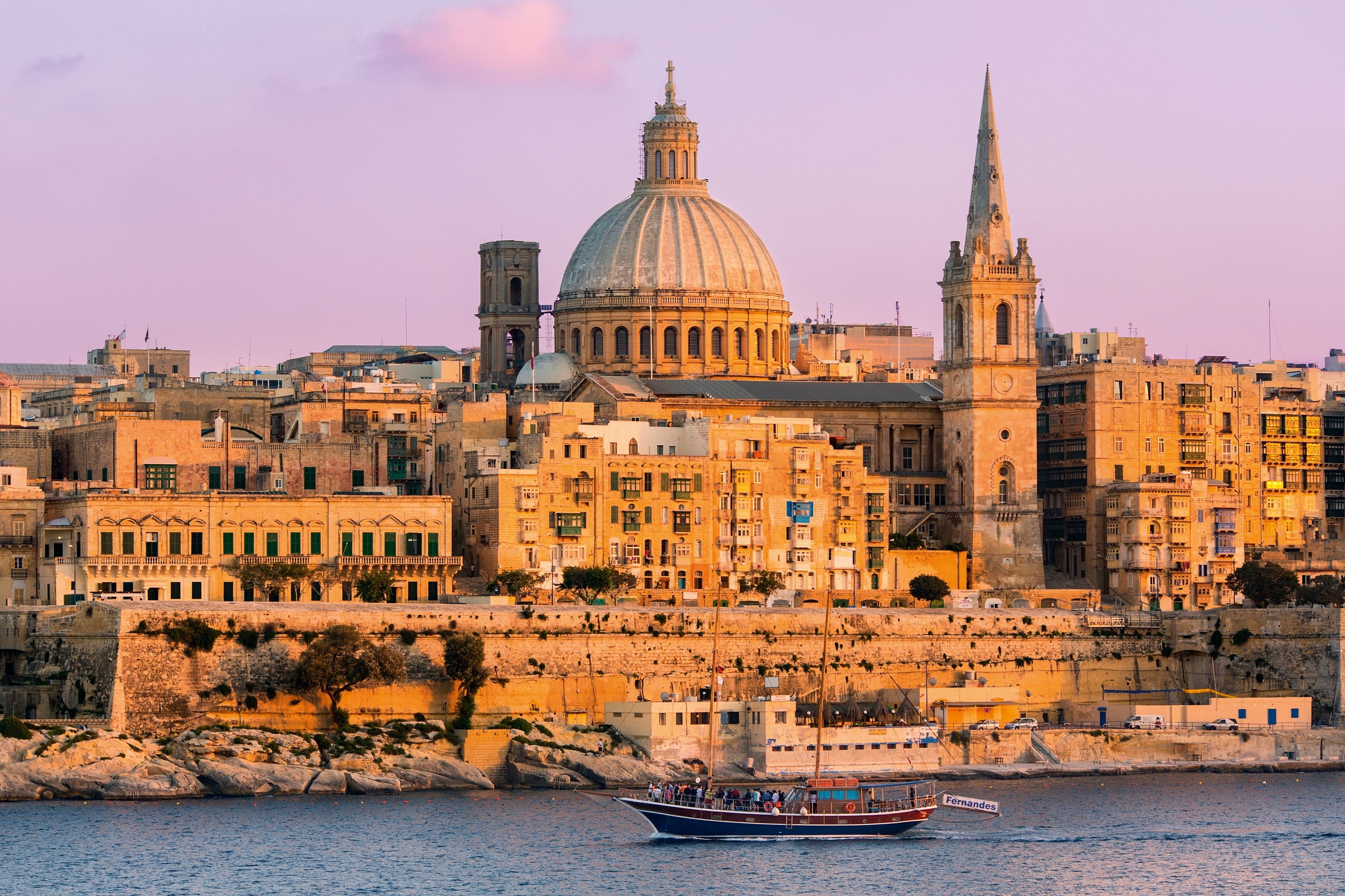 old buildings beside waterfront, foreground features a passing tourist boat