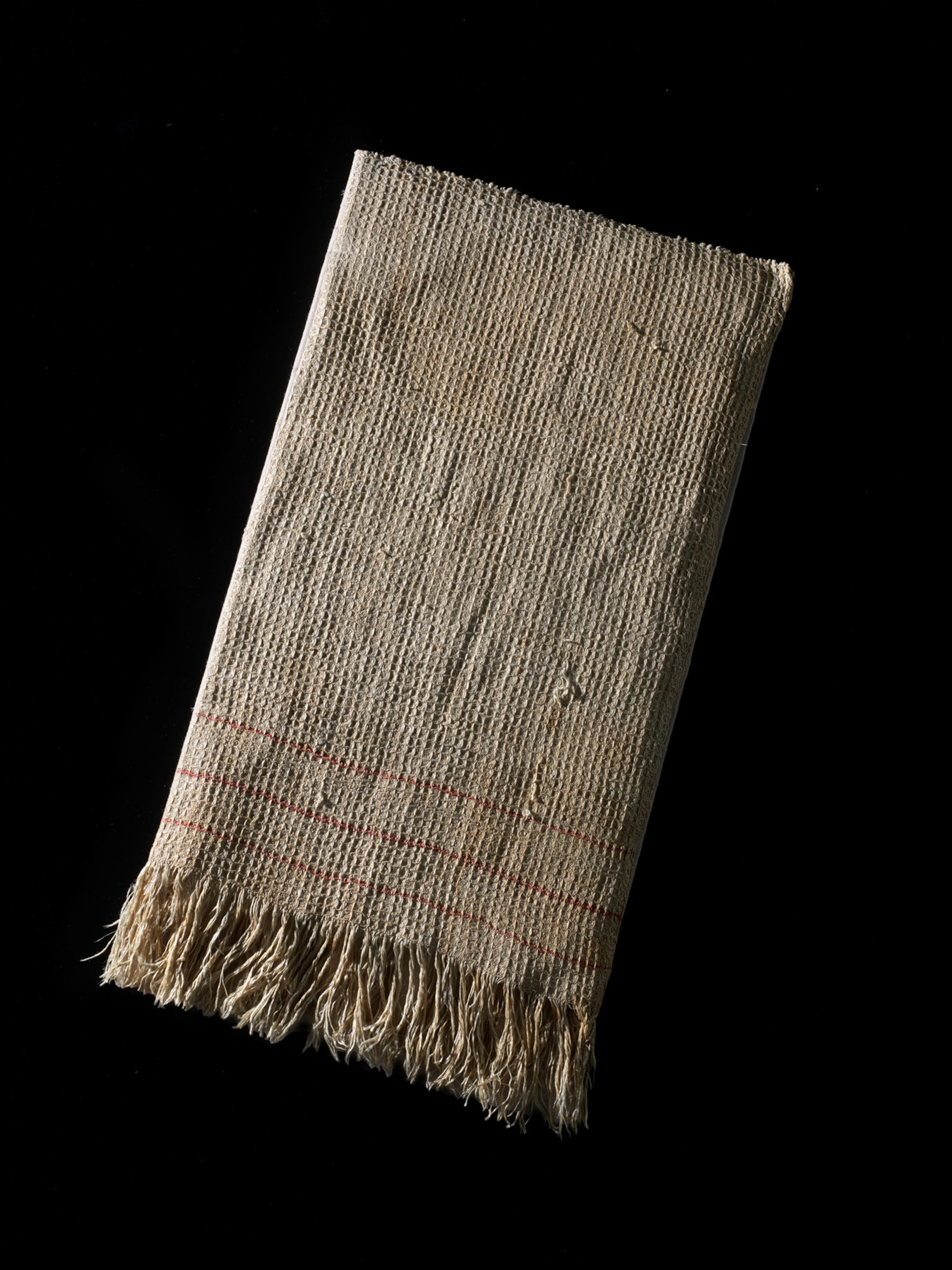 A discolored dishtowel sits on a black background at an angle.
