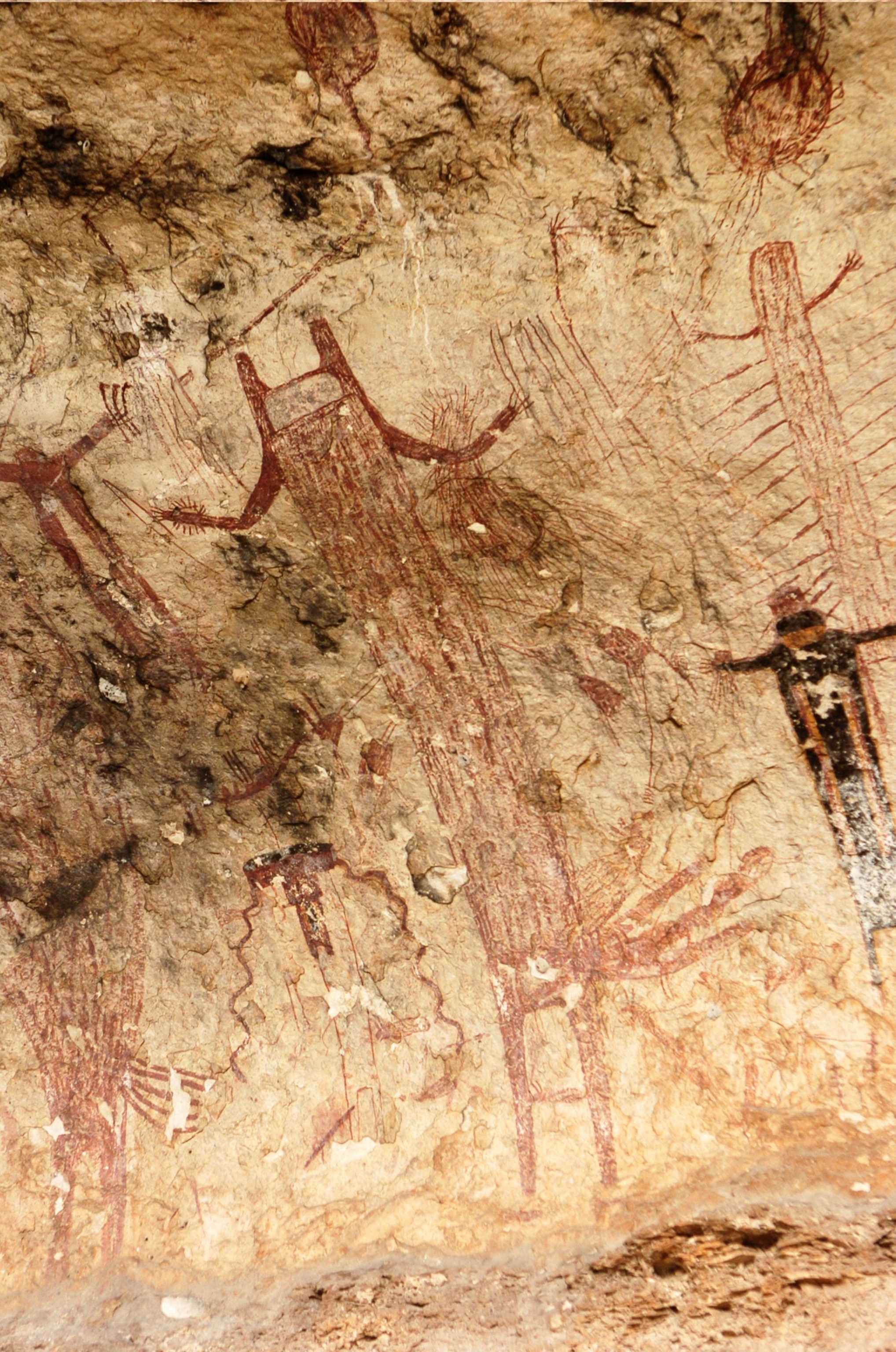 Rock art paintings made with red ink, depicting towering elongated figures.