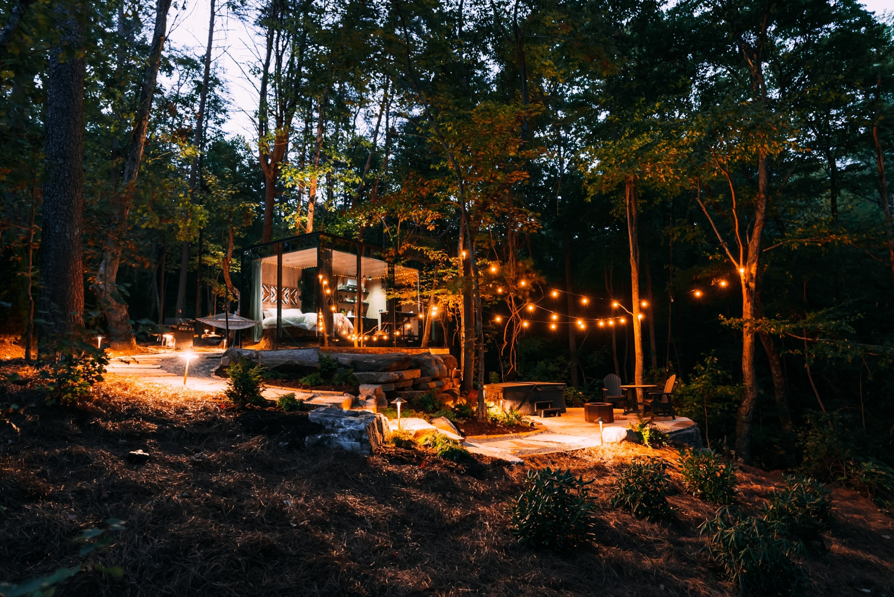 A cabin with floor-to-ceiling windows, lit under strings of lights.
