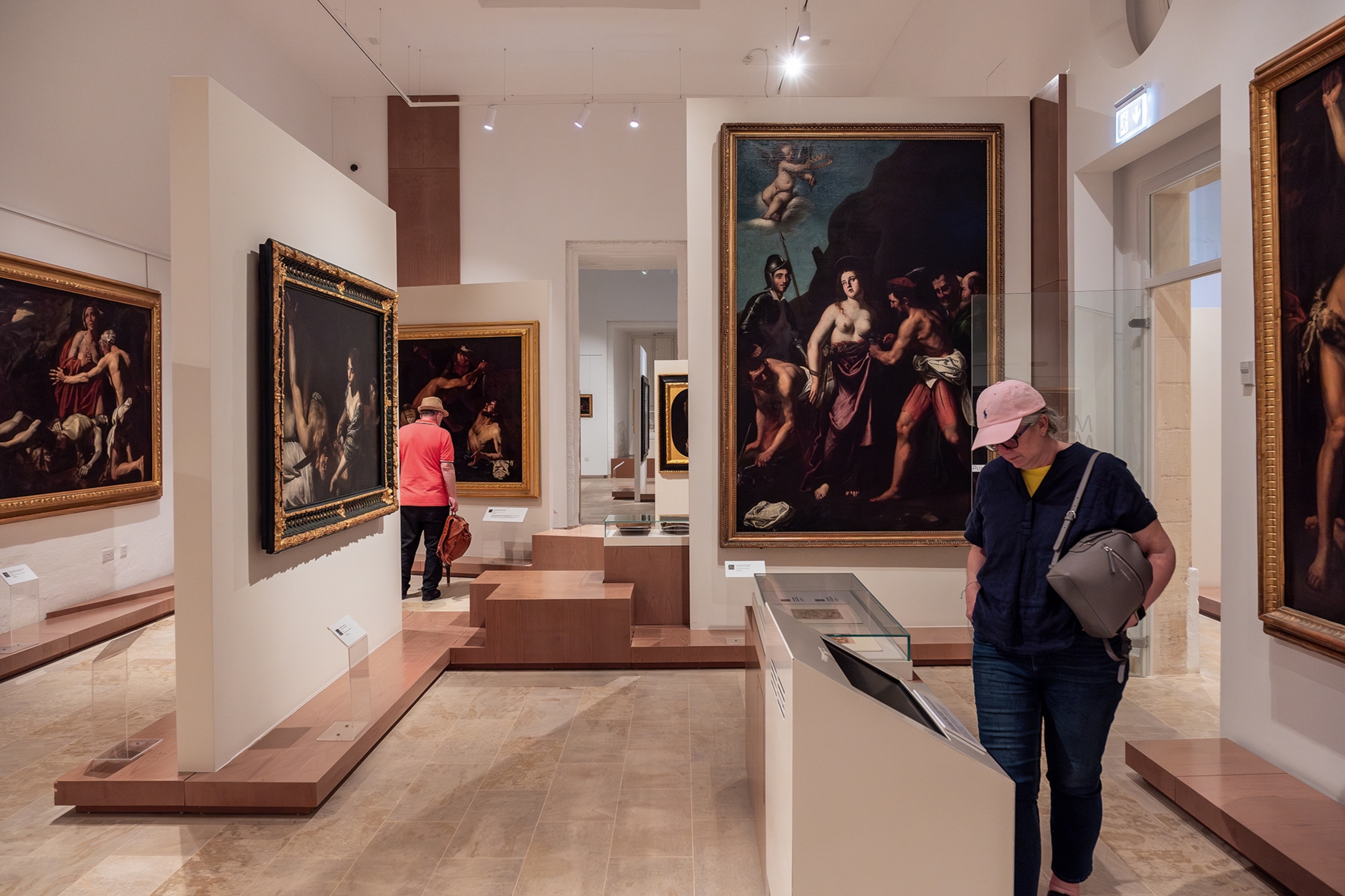 Patrons walk around and view art in a traditional art gallery in Valletta.