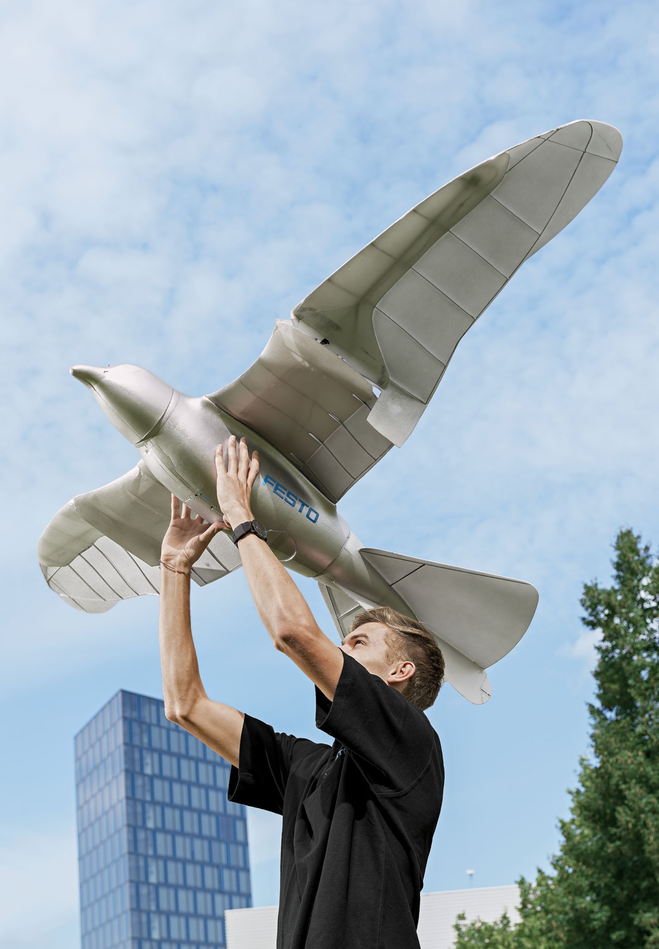 a man holding a large robotic bird modeled after a herring