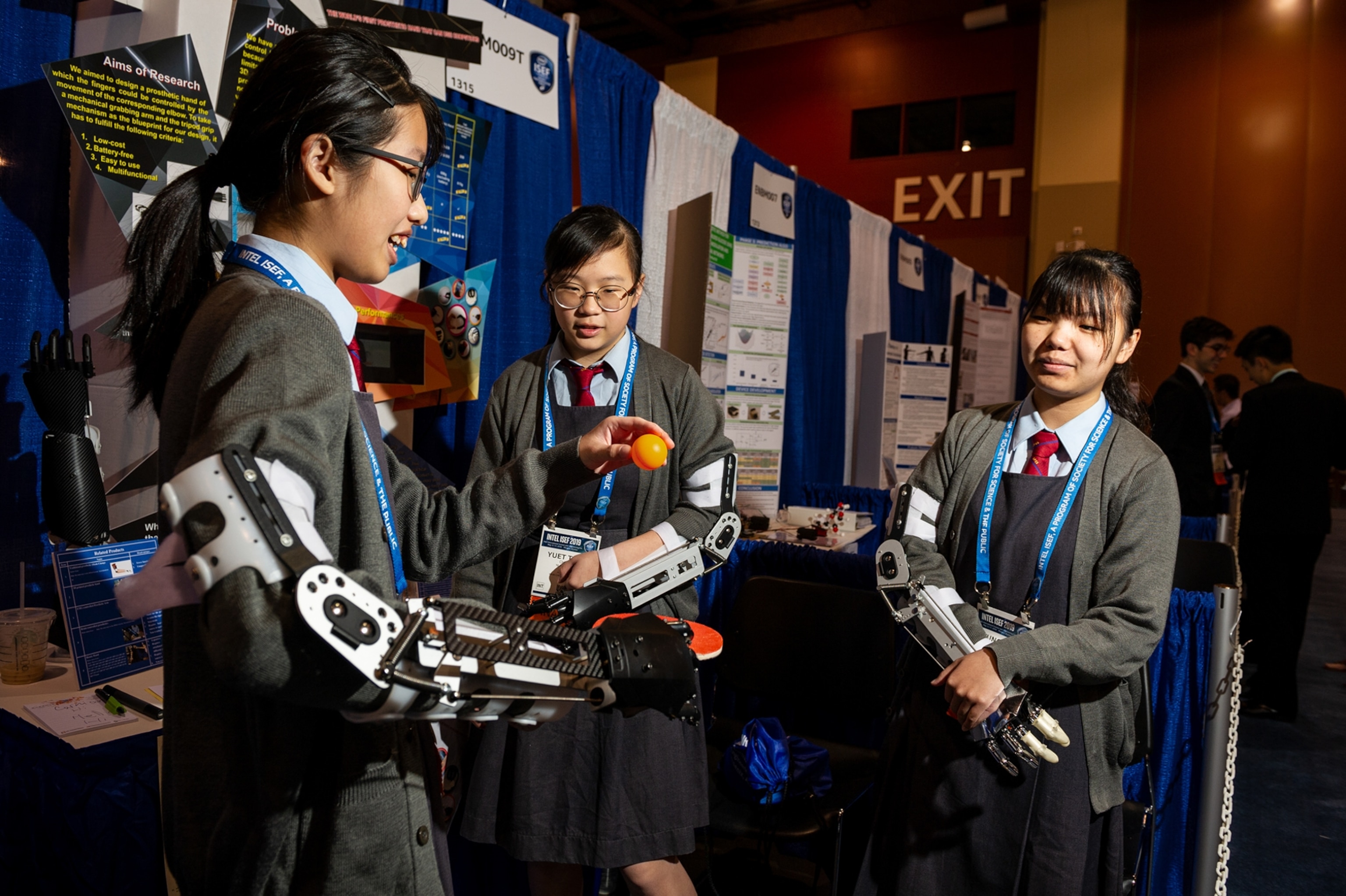 three young women each displaying a prosthetic hand, which covers their forearm