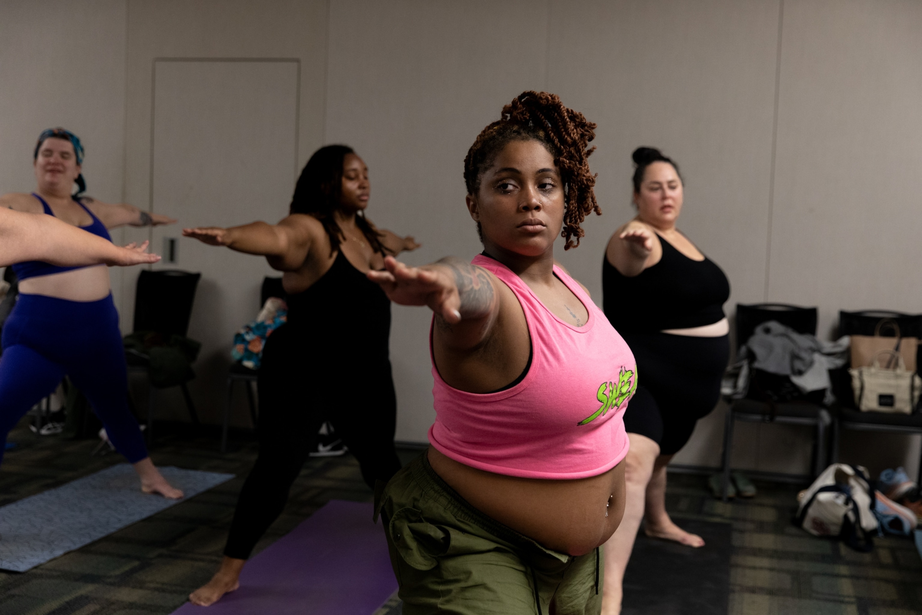 An "overweight" black woman looking strong and focused while participating in a group exercise class.