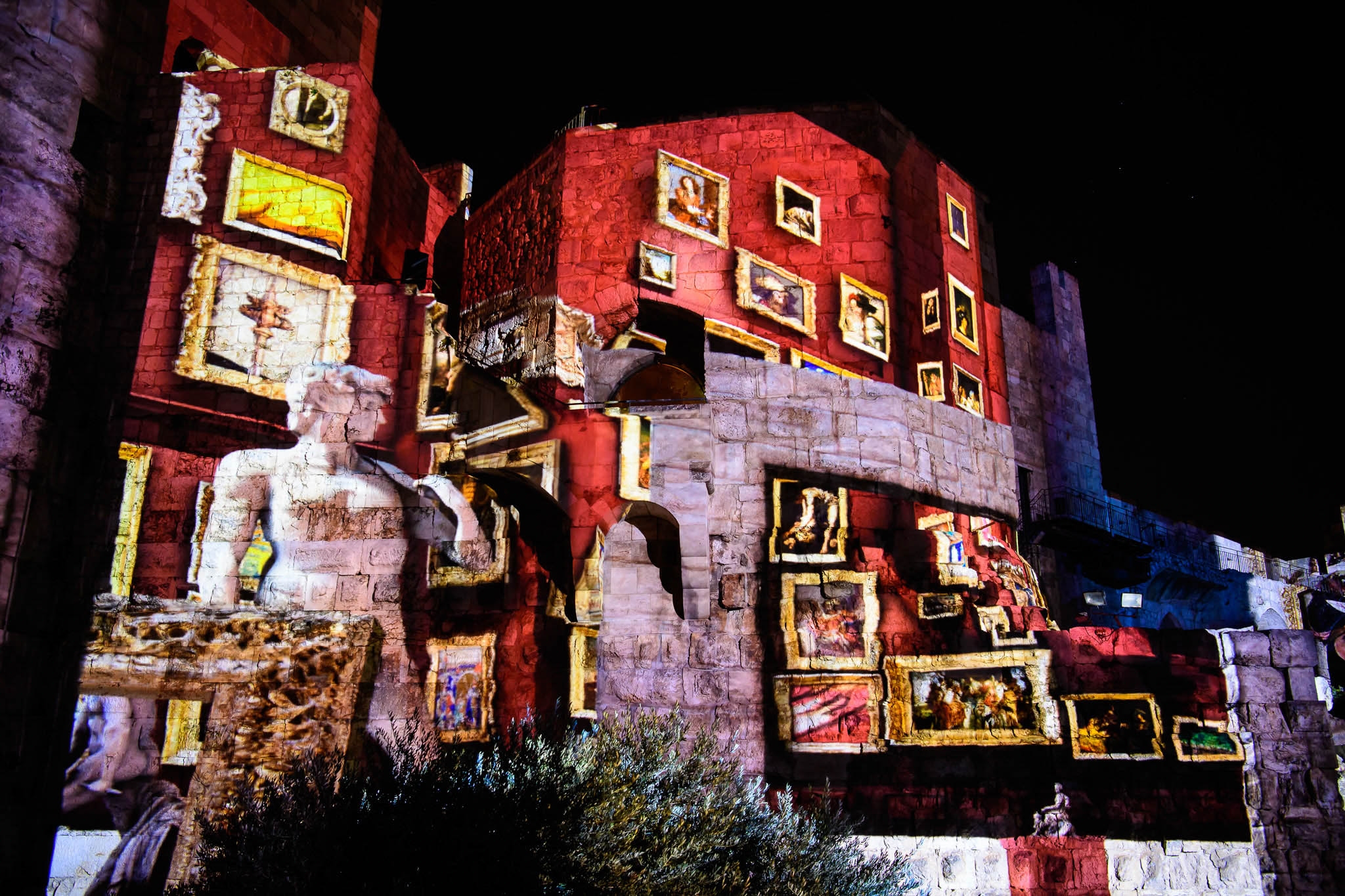 Red walls and figures are projected on historical site.