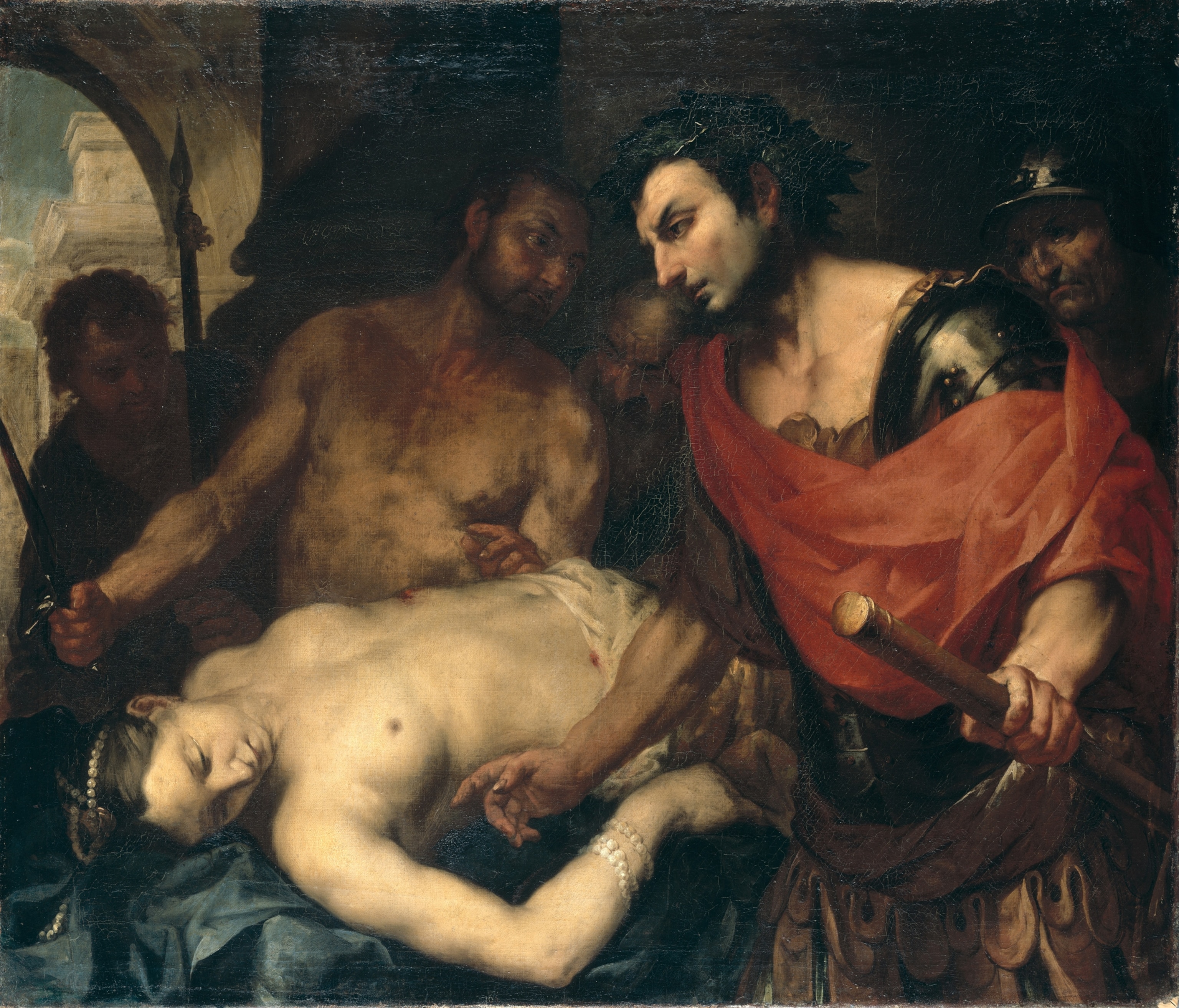 A pale woman (Agrippina) laying down, while a man (Nero) is walking past wearing red fabric cross body. A shirtless man