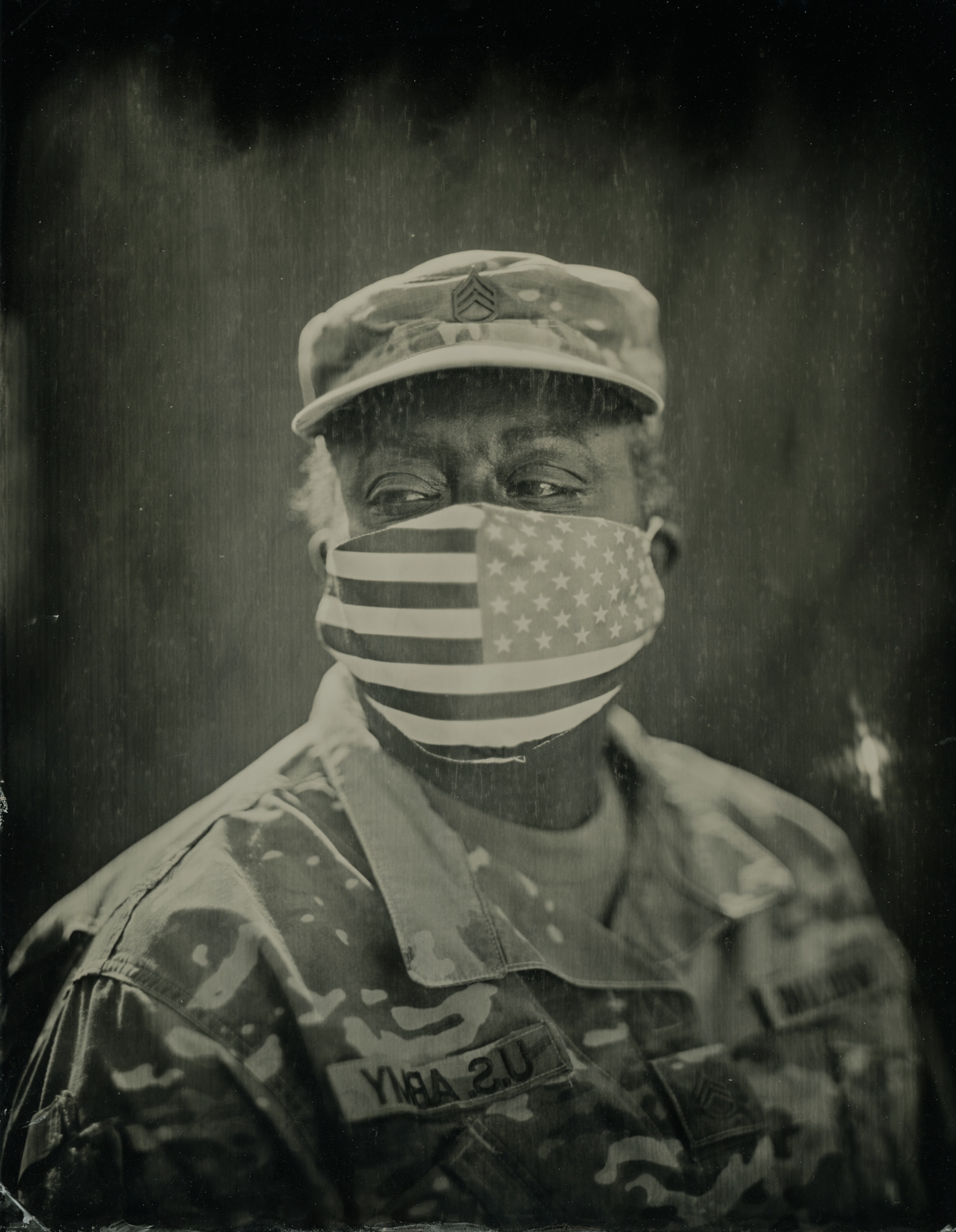 Woman in army uniform looking on while wearing American flag face mask