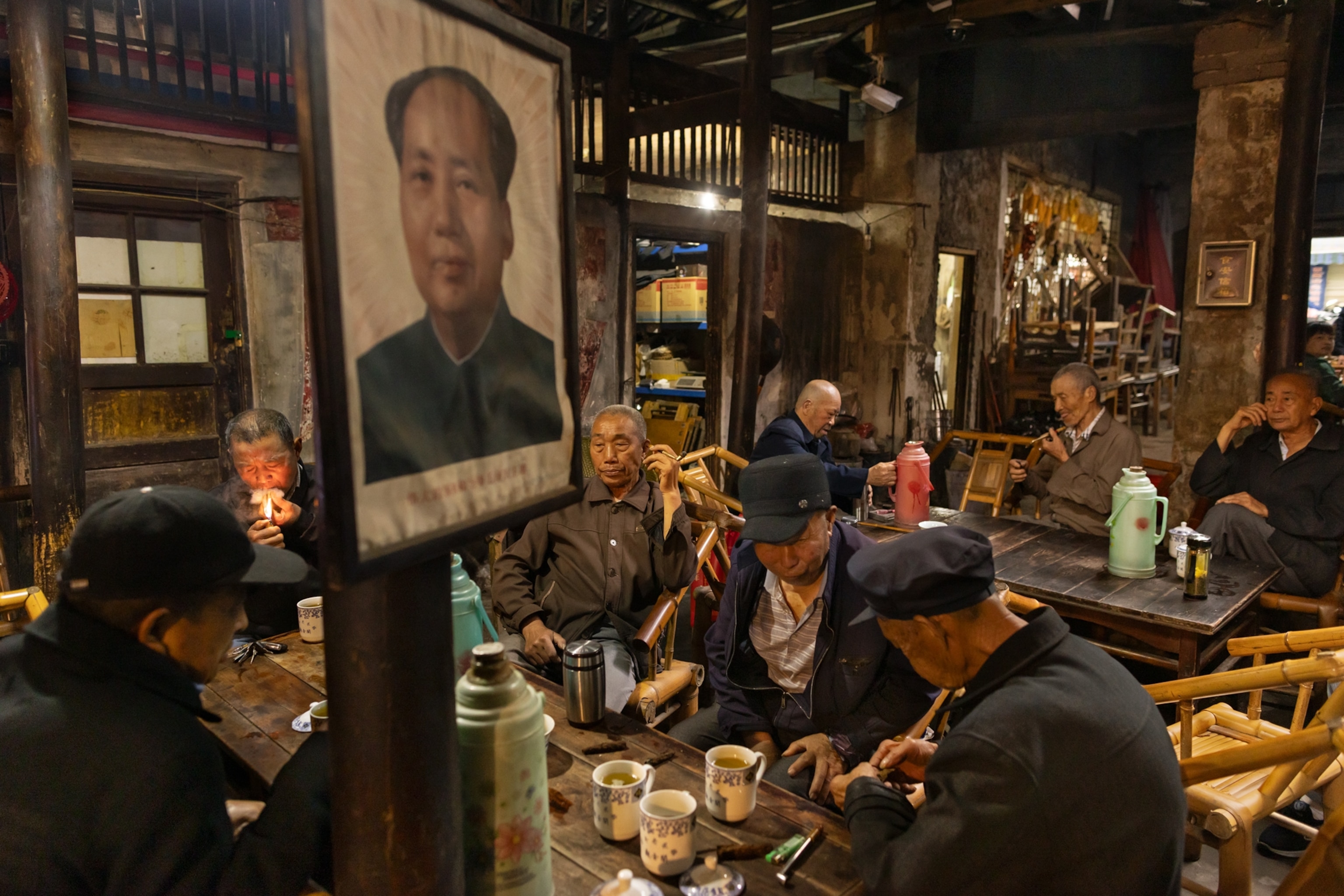 Men having tea with a portrait of Mao Zedong on the wall