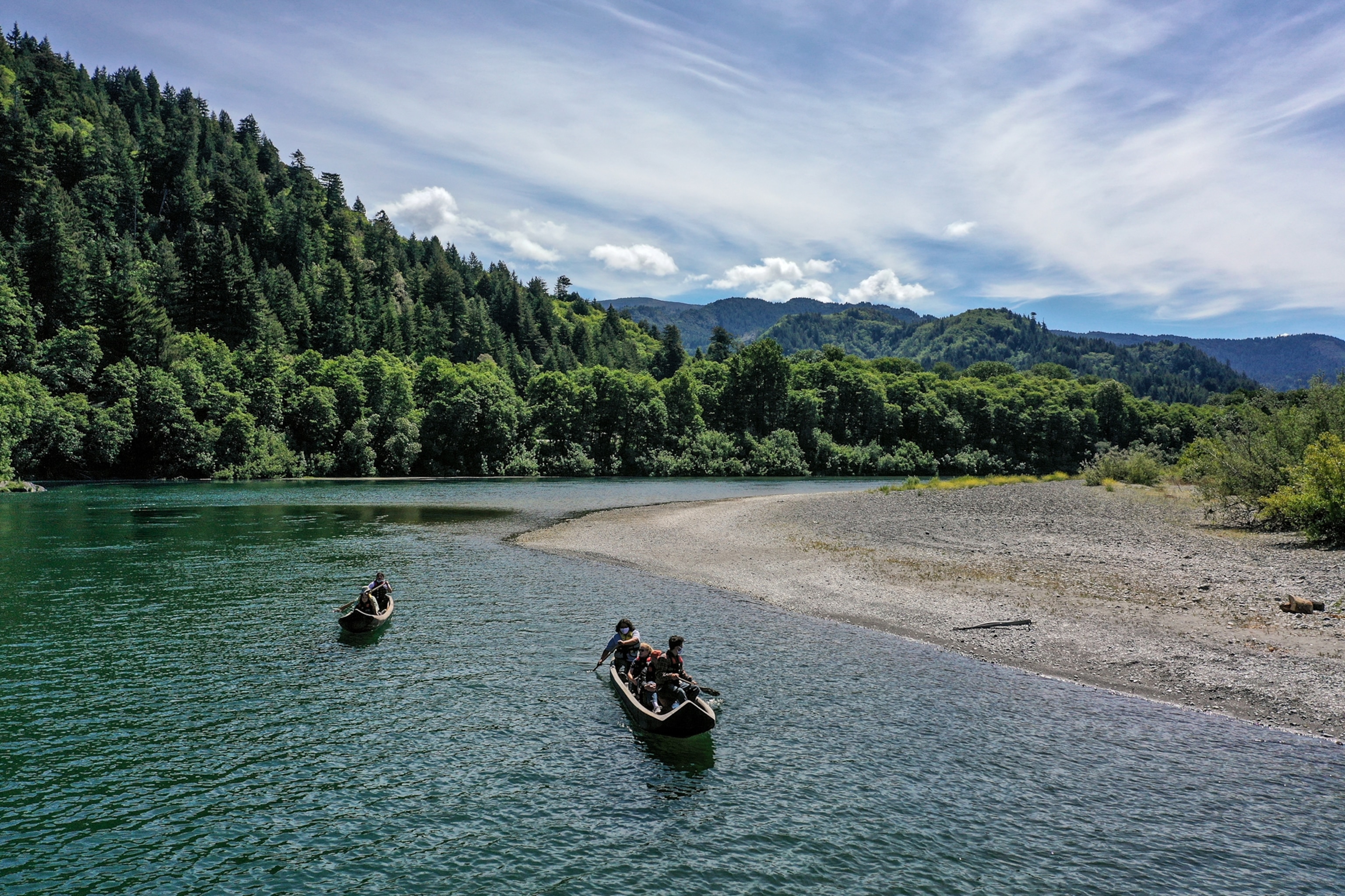 Yurok guides paddle tourists along the Klamath River in traditional canoes hand crafted from Redwood trees