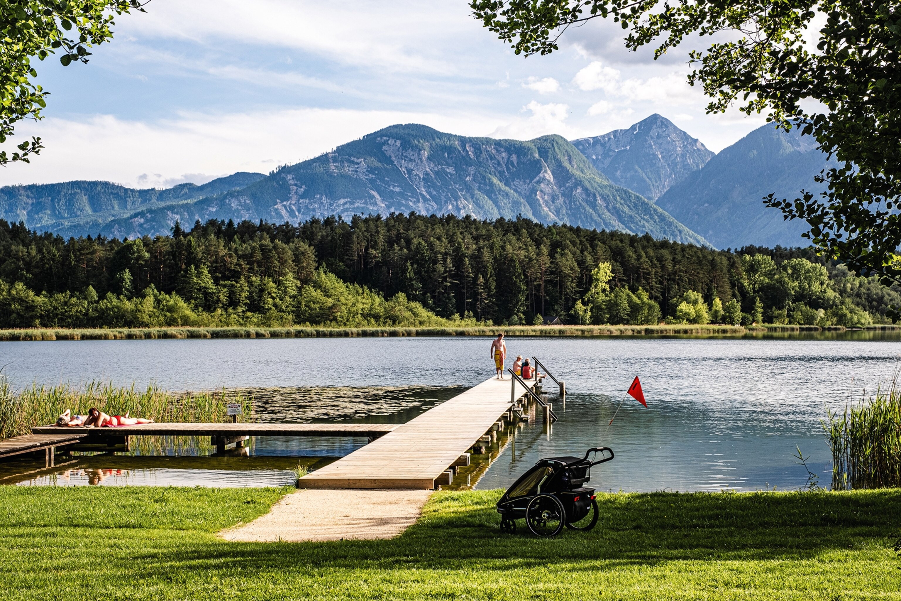 Jetty stretching out into a lake with swimmers perched on the edge