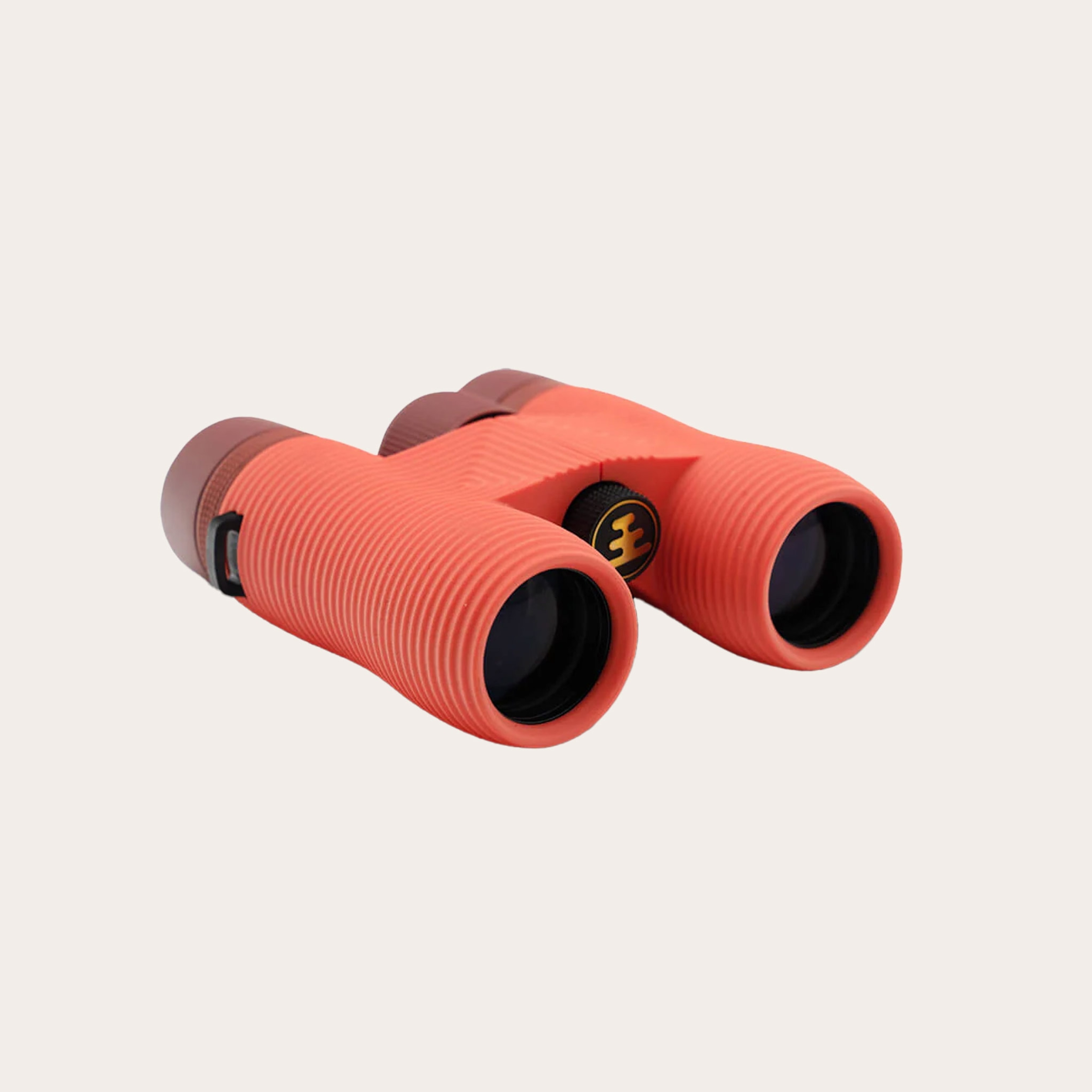 Peach colored binoculars placed on a tan background.