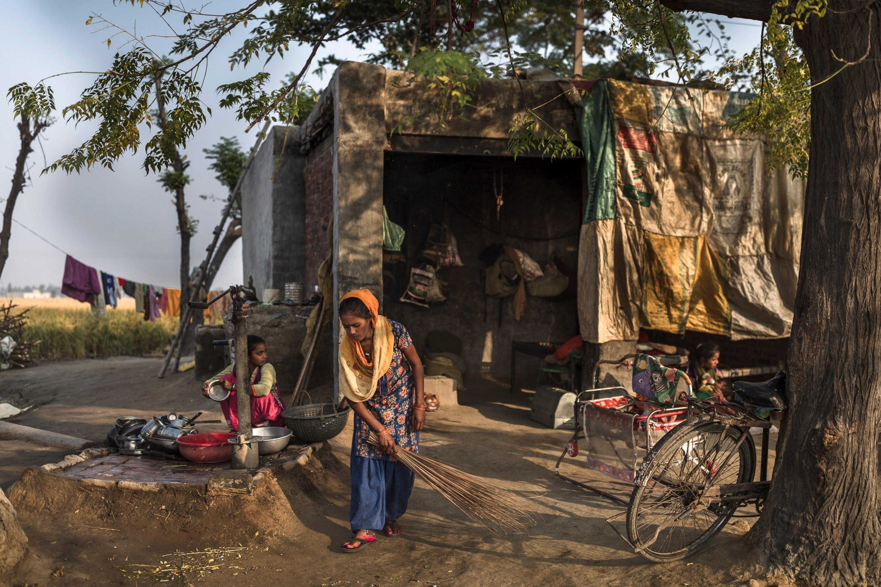 Photo of woman sweeping yard in front of her house.