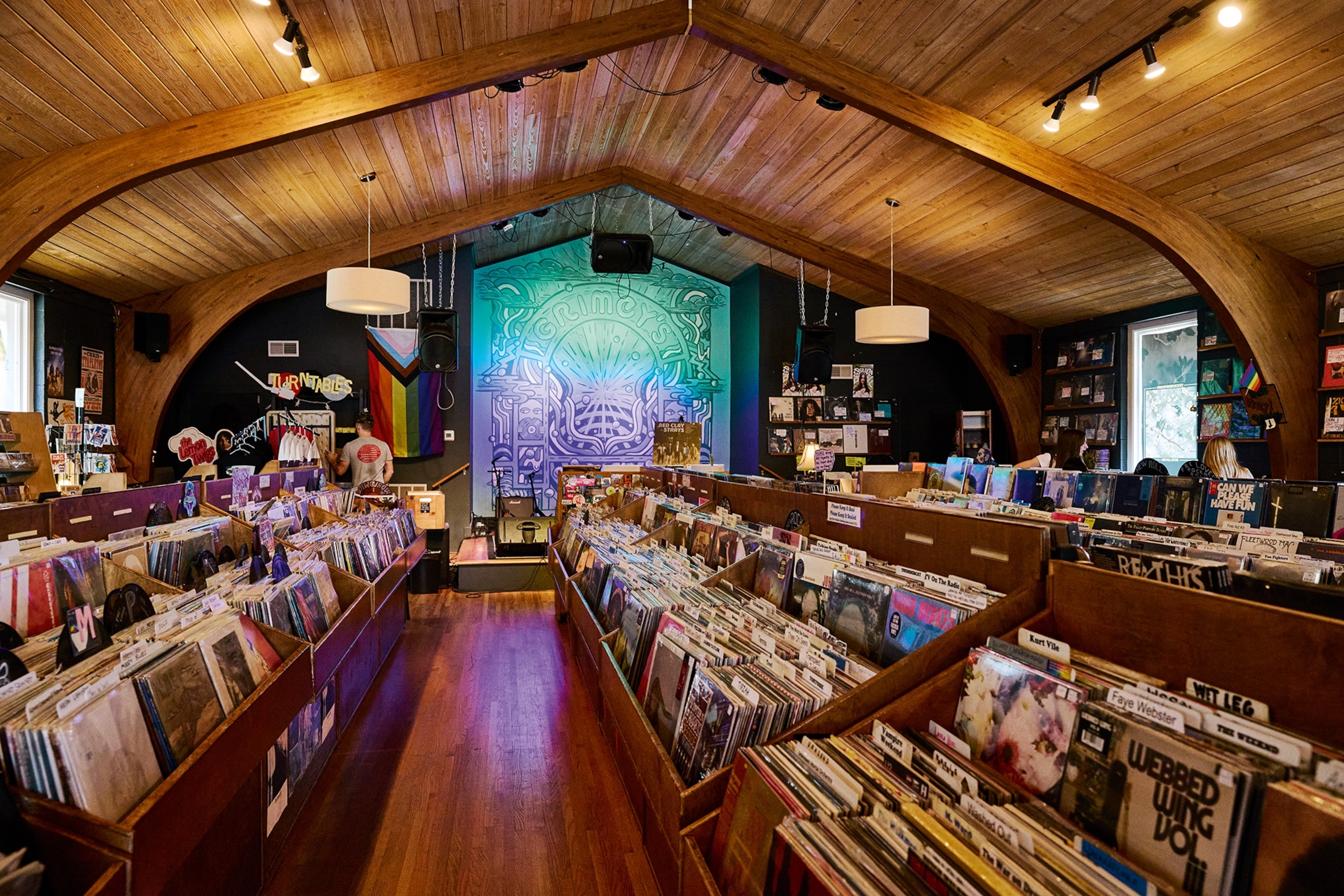 A look inside a vinyl record shop in a restored wooden church with a small stage in the back.