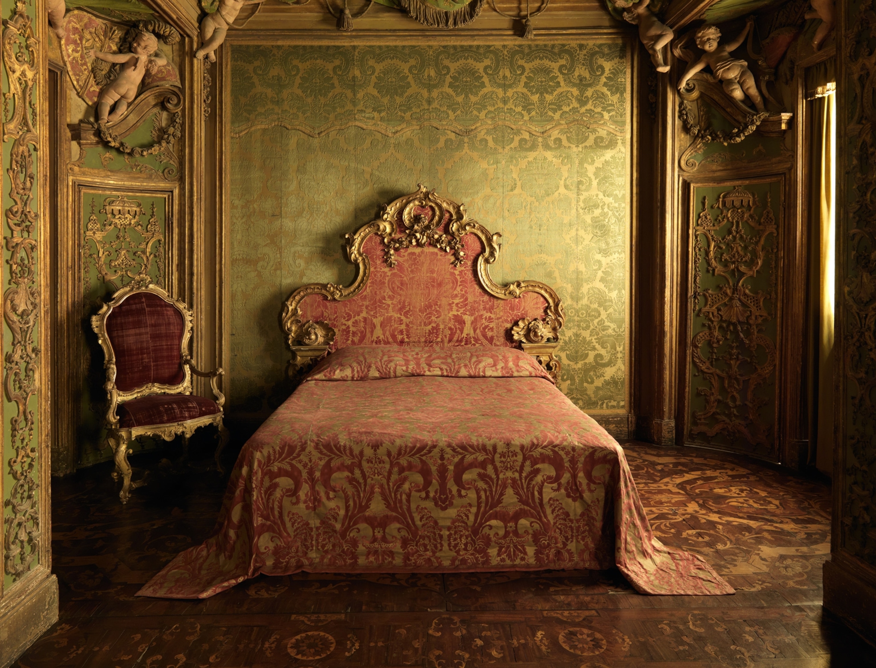 The bedroom from the Sagredo Palace; an elaborate red bedspread against a green and gold decorated walls.