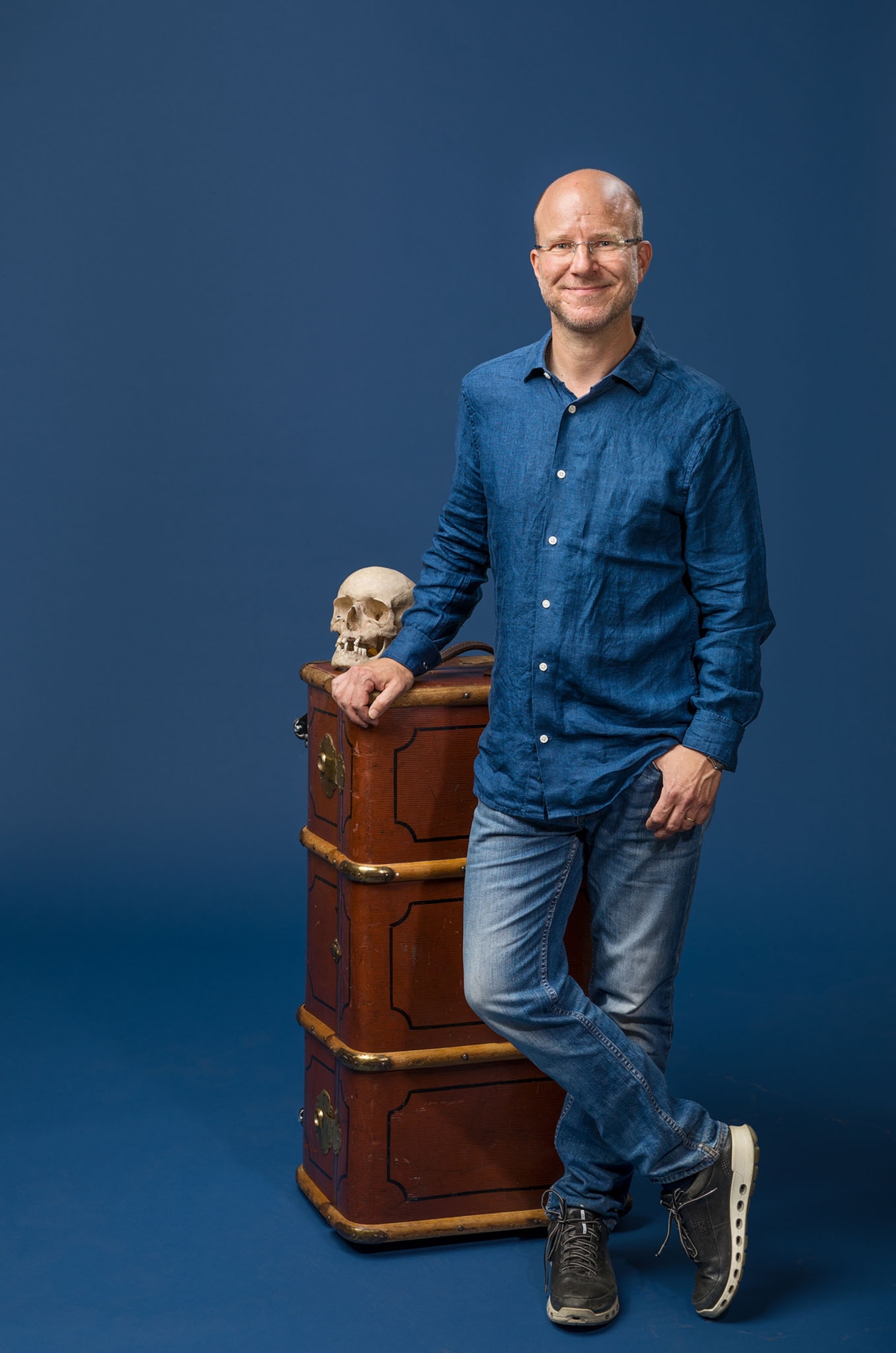 man in blue jeans and human skull on the trunk