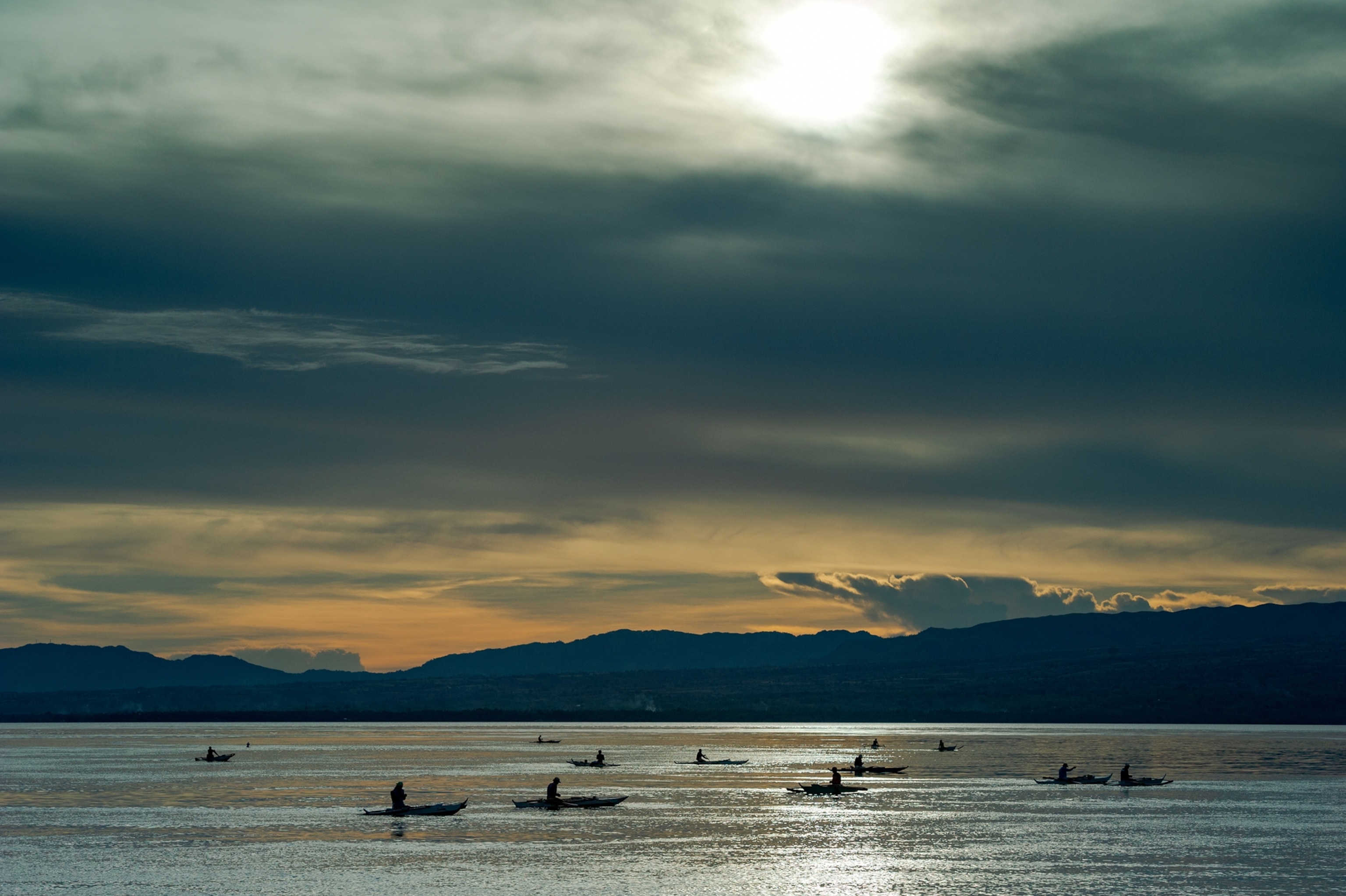 Picture of a group of fisherfolk silhouetted against the water.
