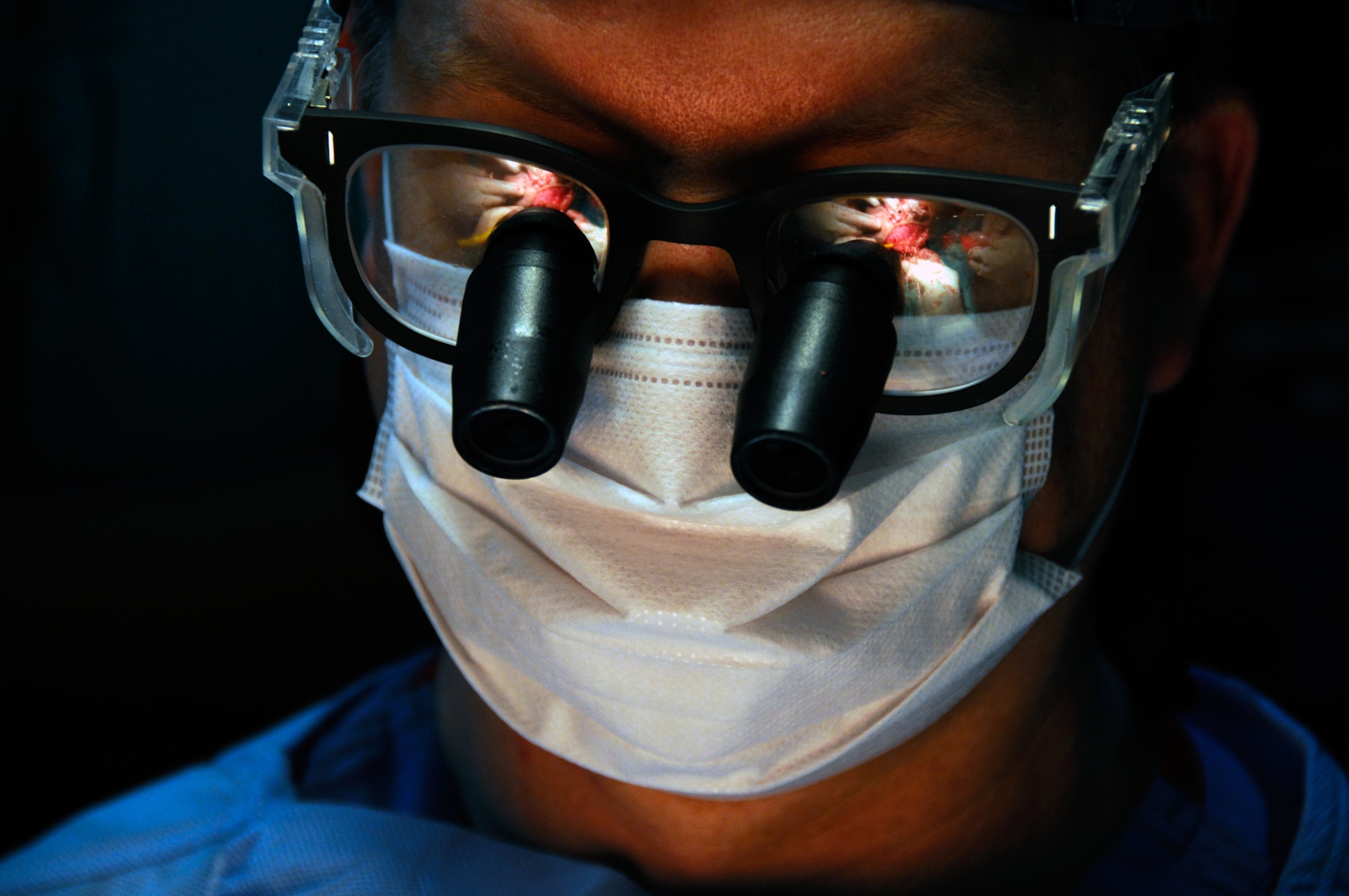 A close-up view of a surgeon's glasses, which are reflecting the operating table during surgery