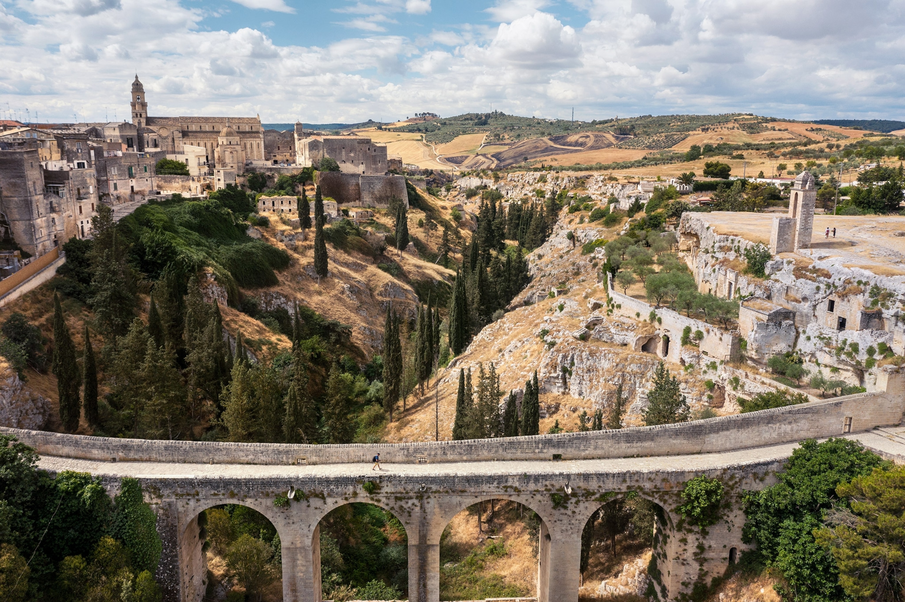 A person walks along the Ponte dell’Acquedotto and crosses a ravine in Italy