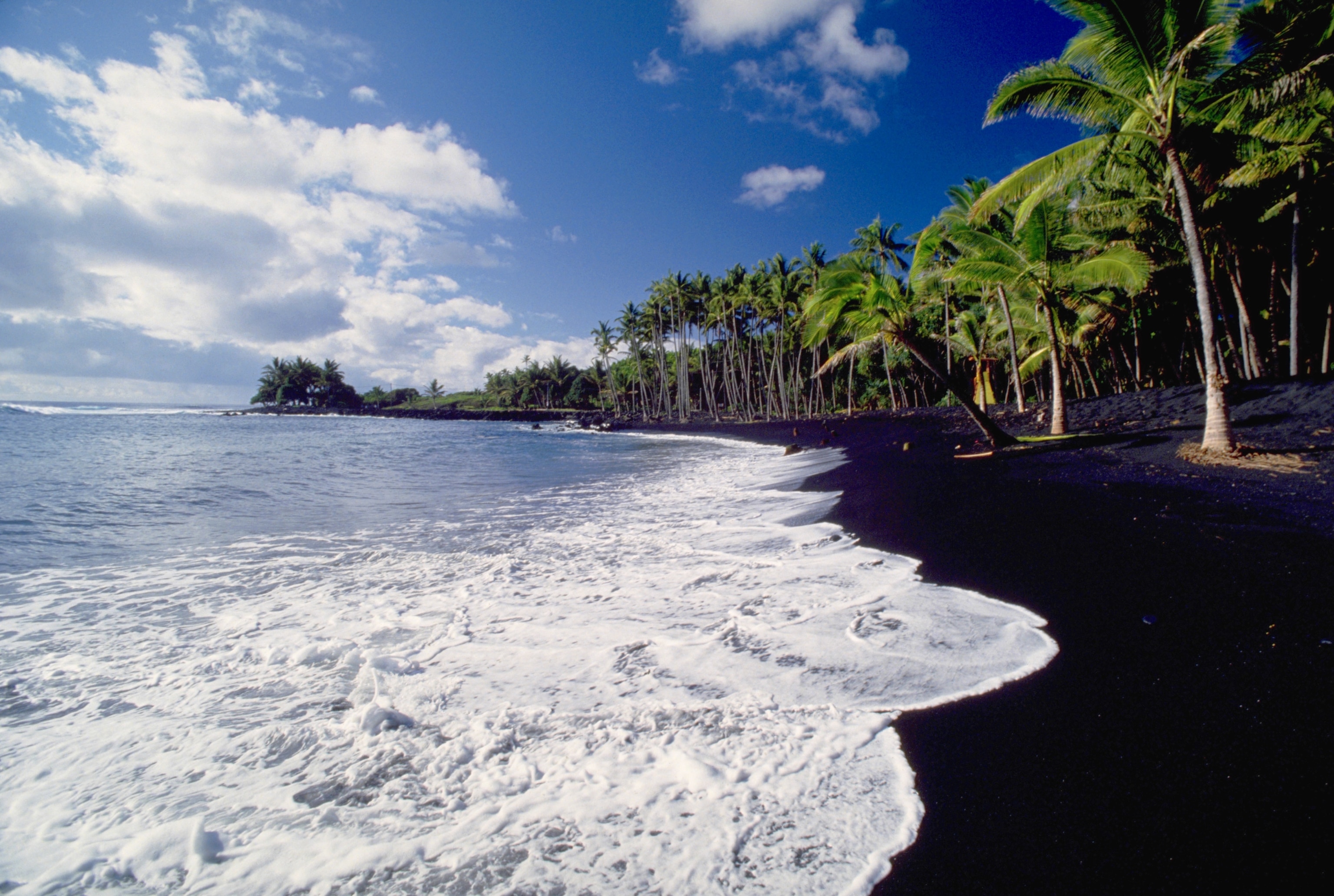 the surf on black sand of Kaimu Beach in Hawaii