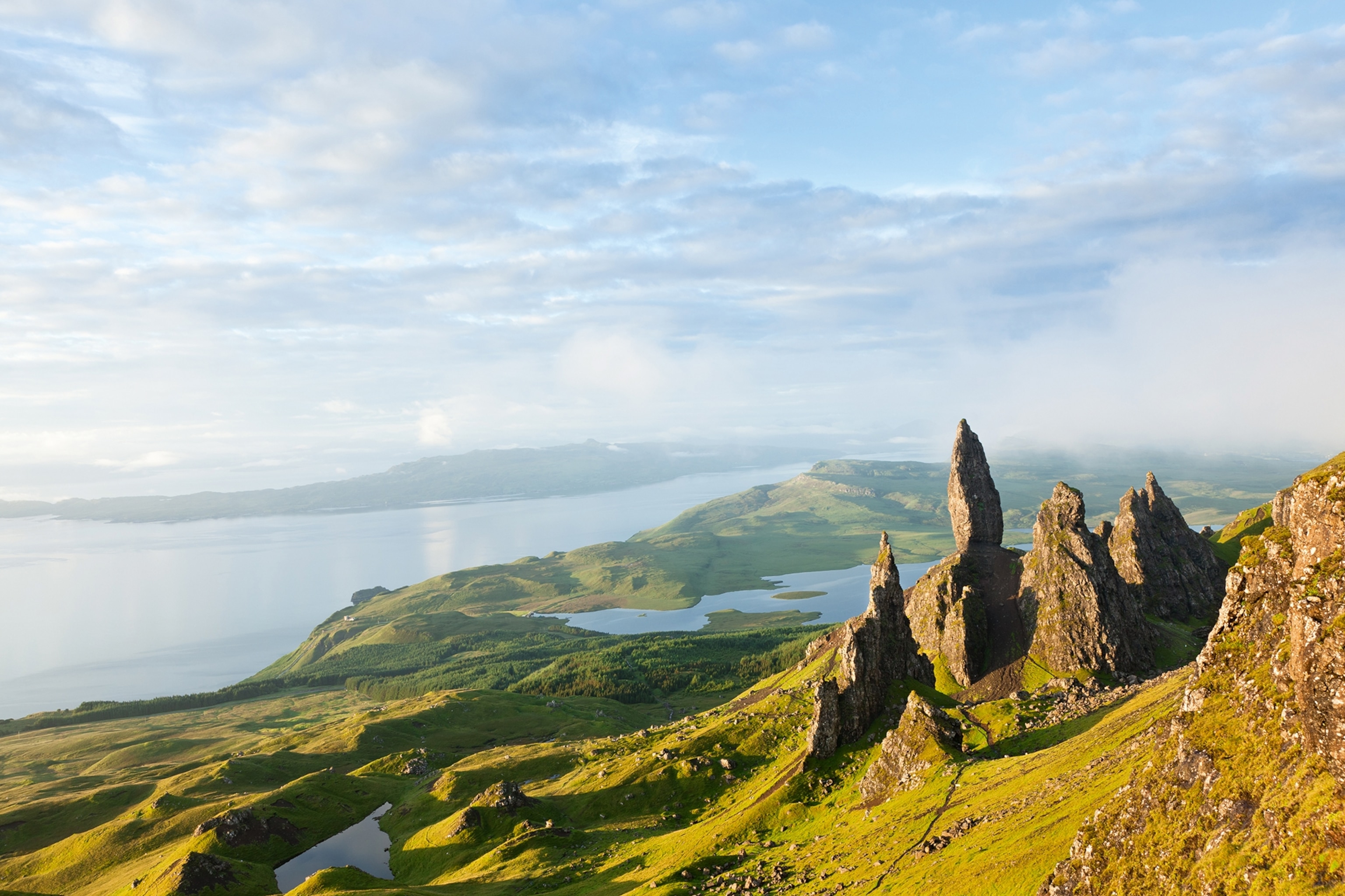 The Old Man of Storr rock formation looking over lochs and green landscapes