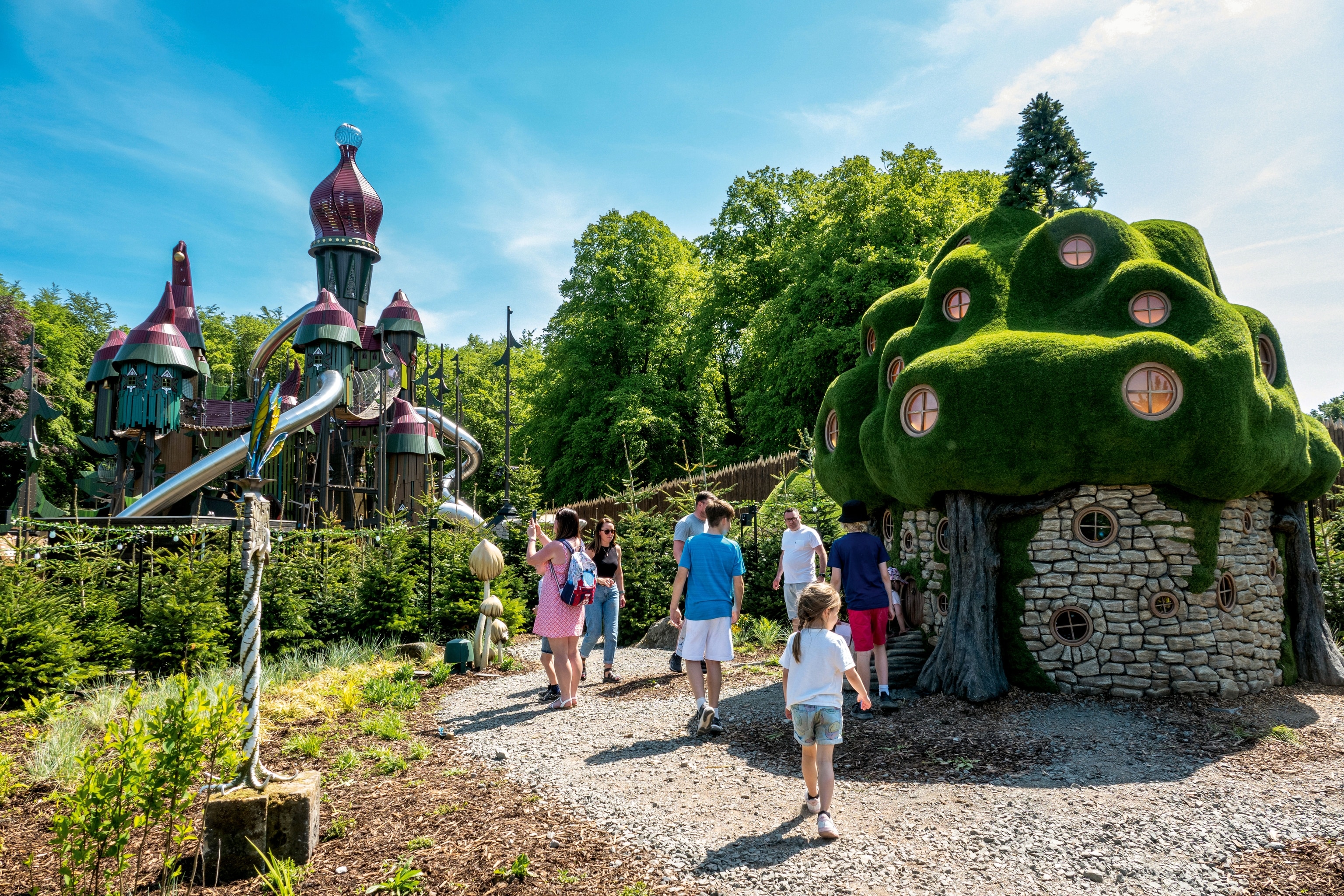 families exploring play village - brightly lit, green and stony