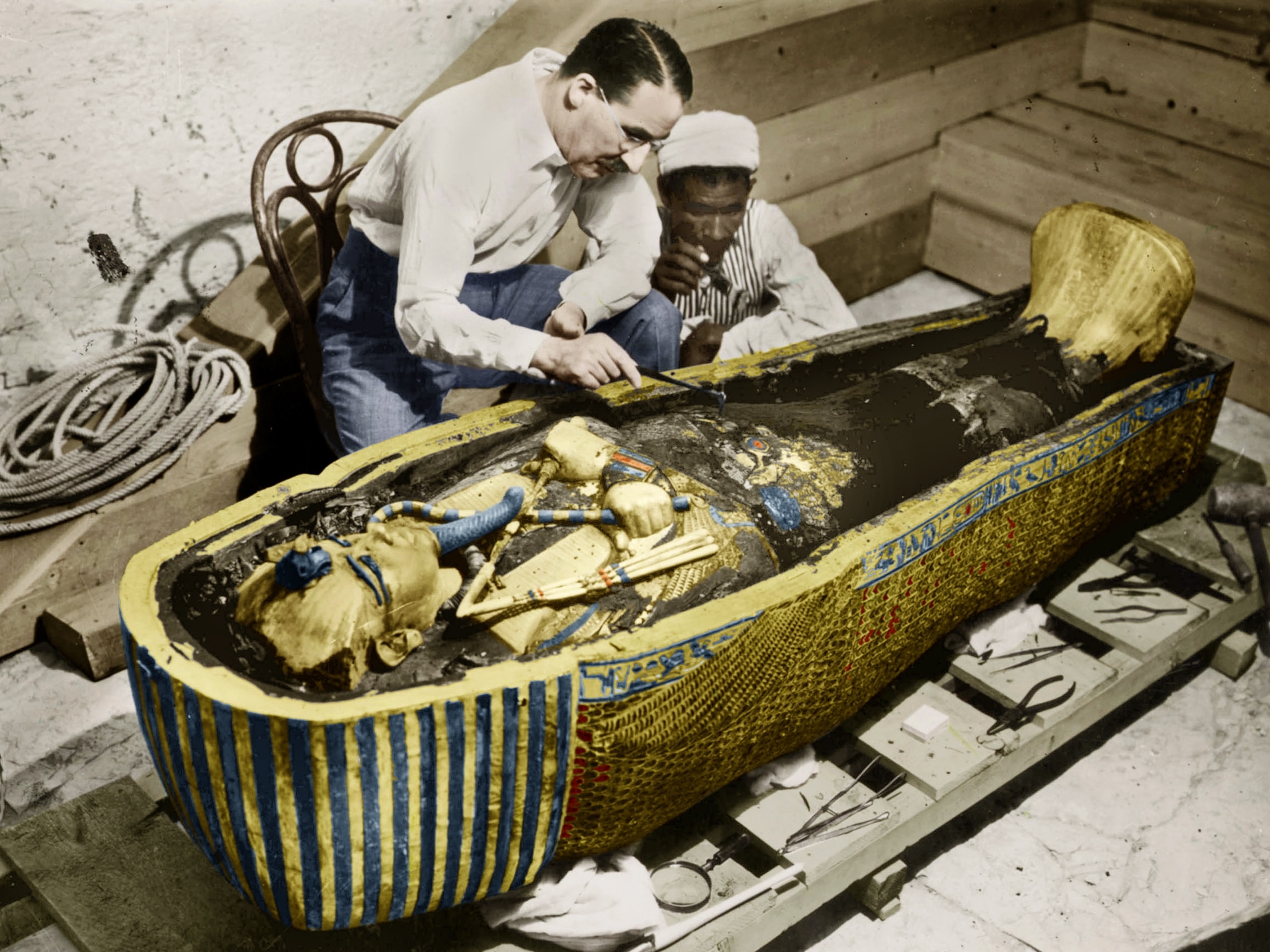 Howard Carter examines the sarcophagus of ''King Tut'' in a hand-colored photograph.