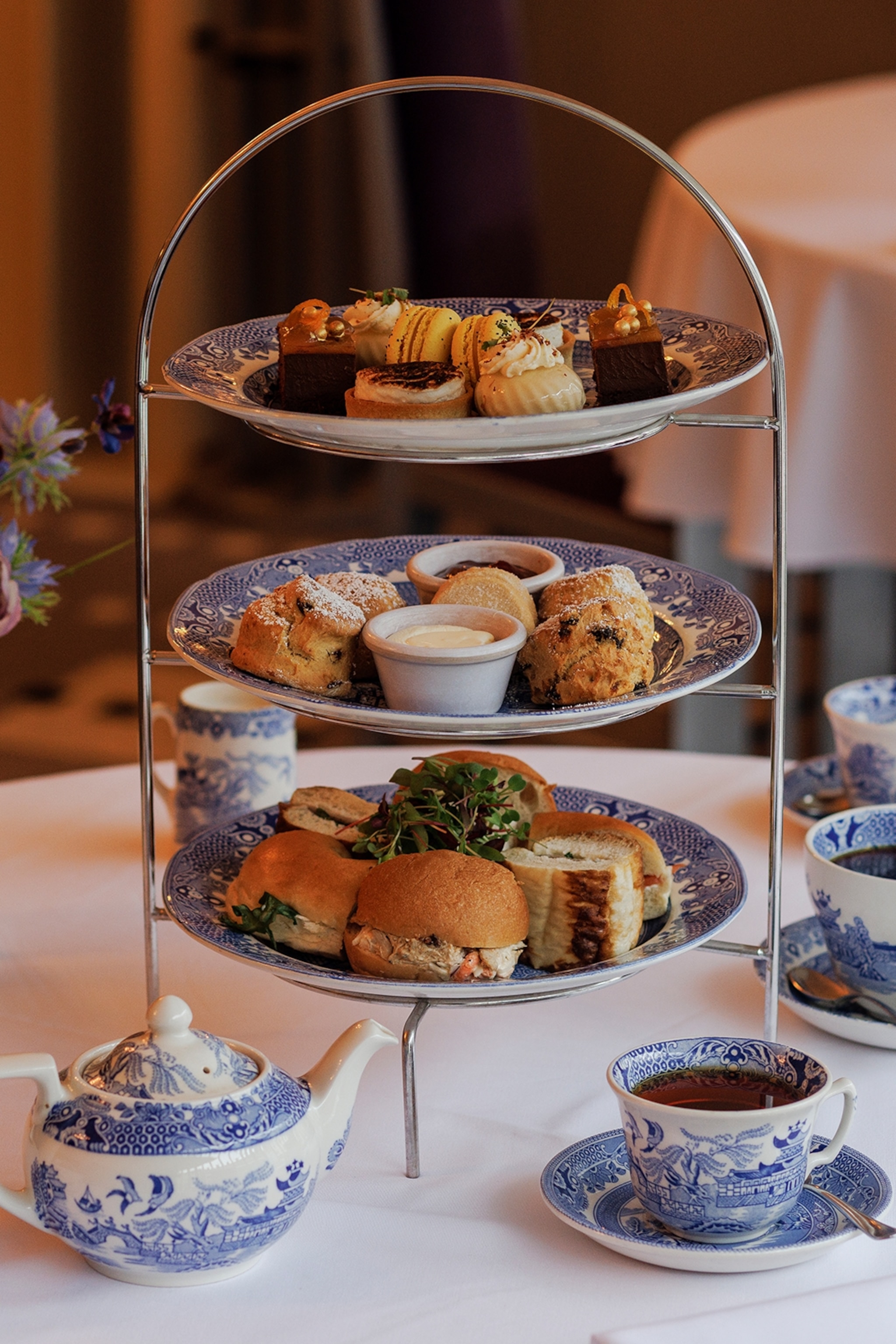 A ceramic etagiere with pastries and tea served on the side.