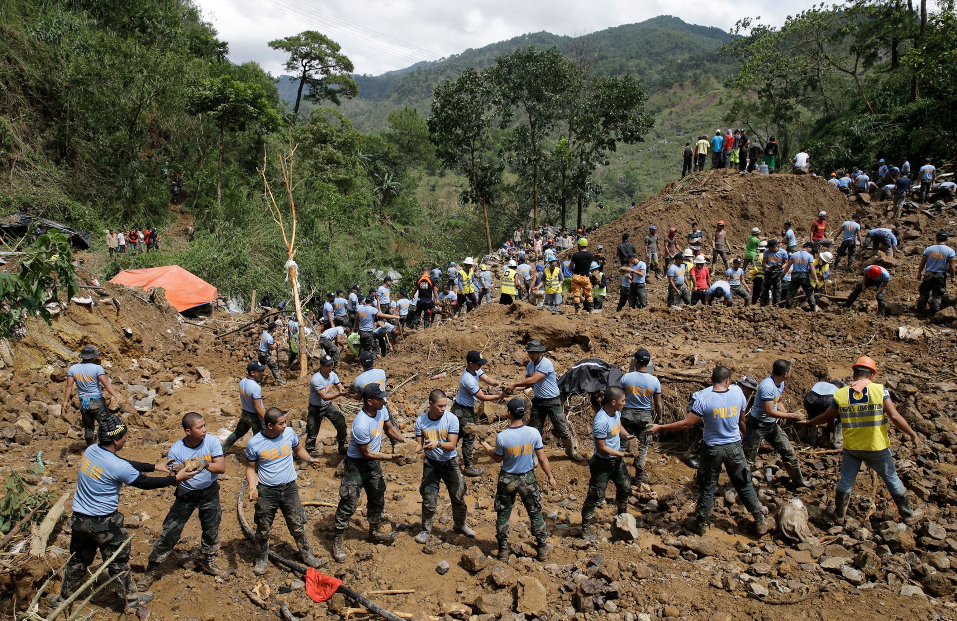 rescuers moving stones at the site where victims are believed to have been buried.