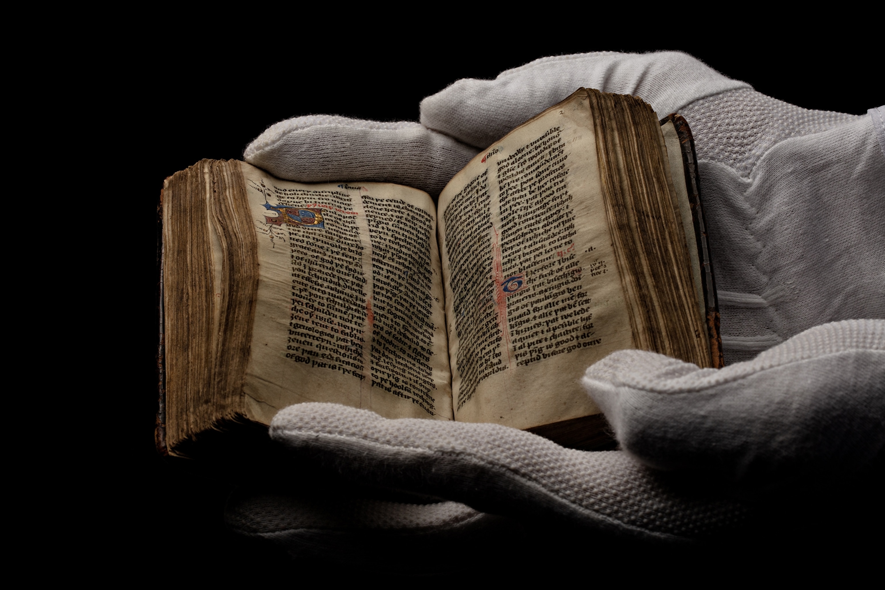 hand in white gloves holding an open book